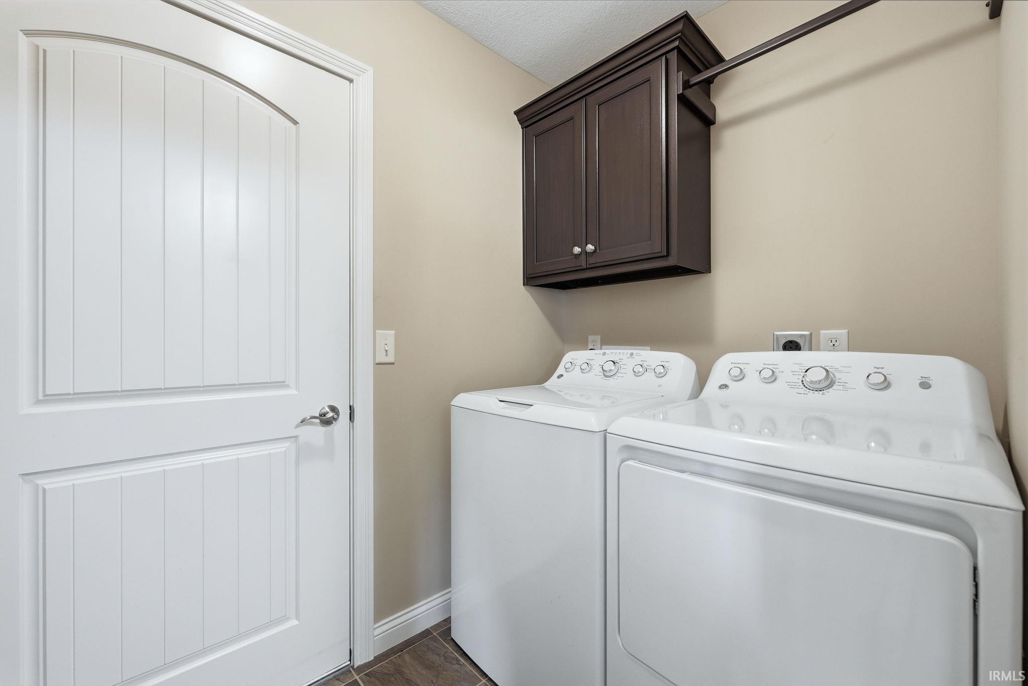 Laundry area featuring washer and dryer, cabinet space, and dark wood-style floors