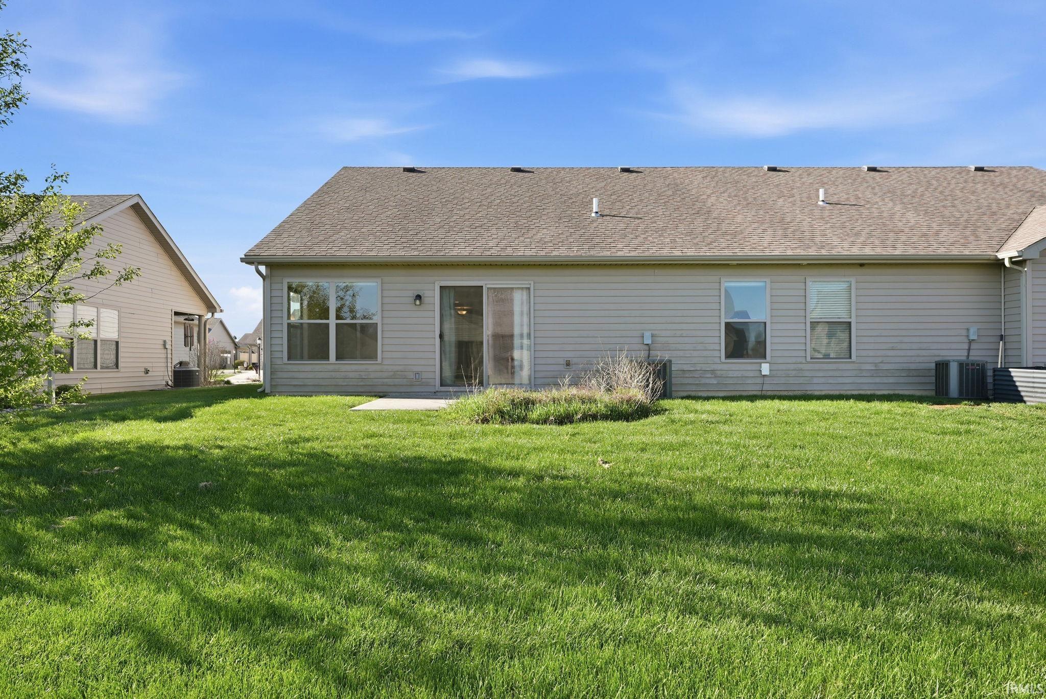 Back of property featuring a patio area, a lawn, and a shingled roof