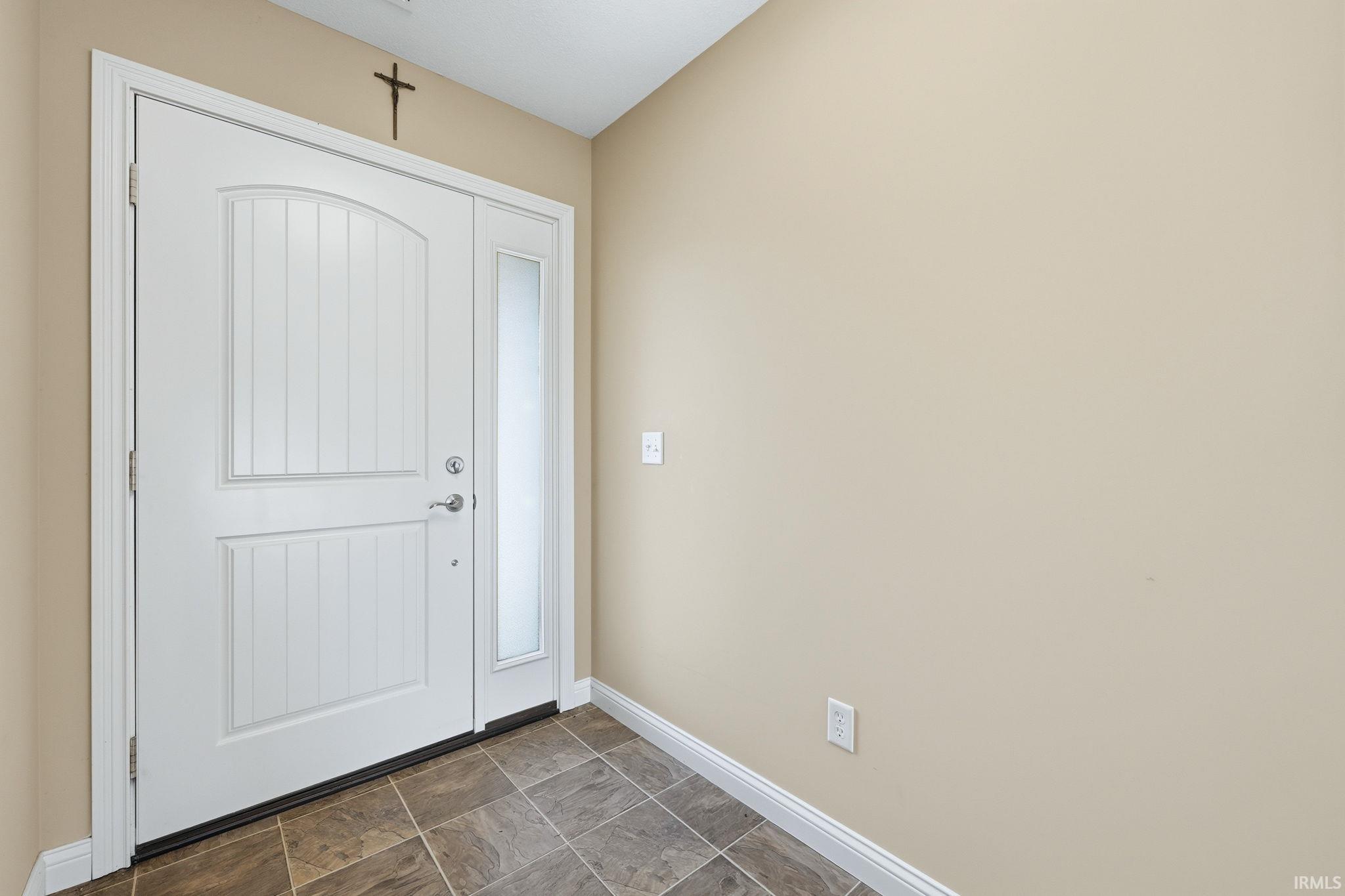 Foyer entrance with stone finish flooring and baseboards