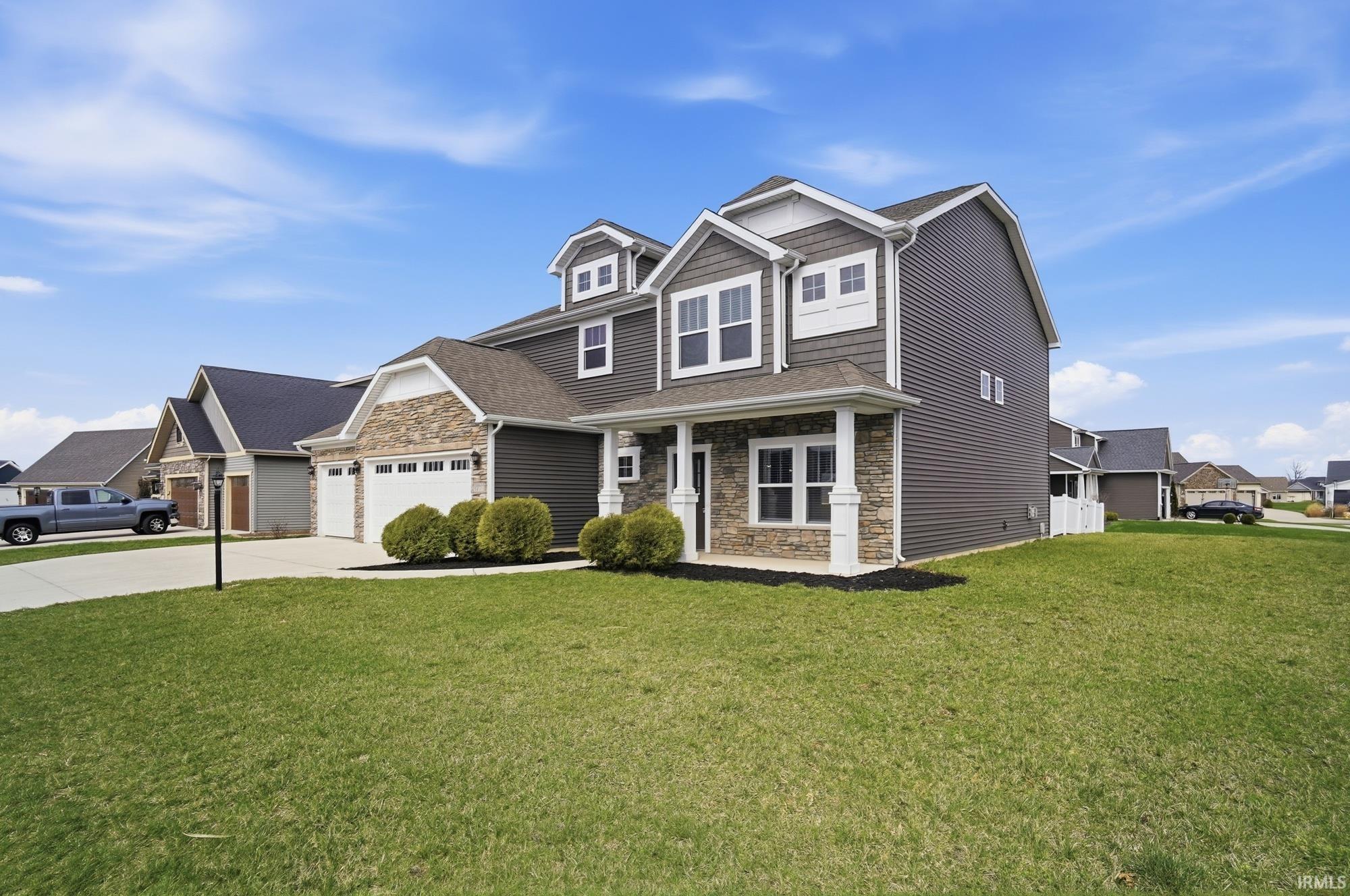 Craftsman-style home with stone siding, concrete driveway, a front yard, and a porch
