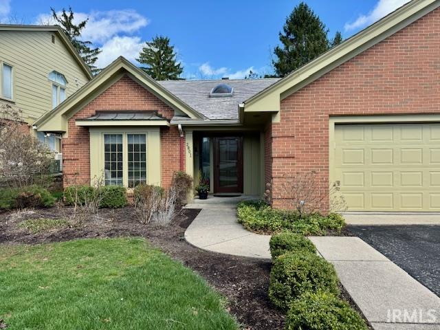 Entrance to property with brick siding, a garage, and a yard