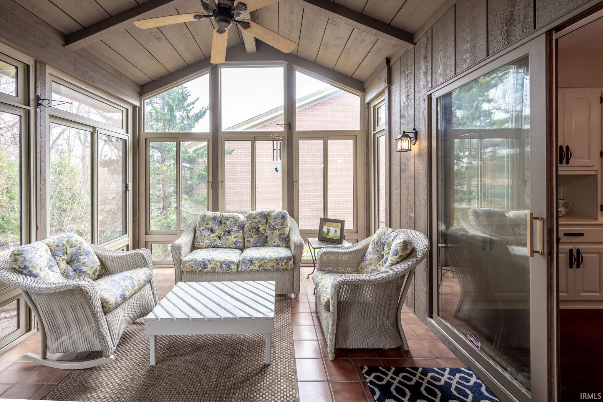 Sunroom featuring outdoor seating, beamed ceiling, plenty of natural light, and a ceiling fan