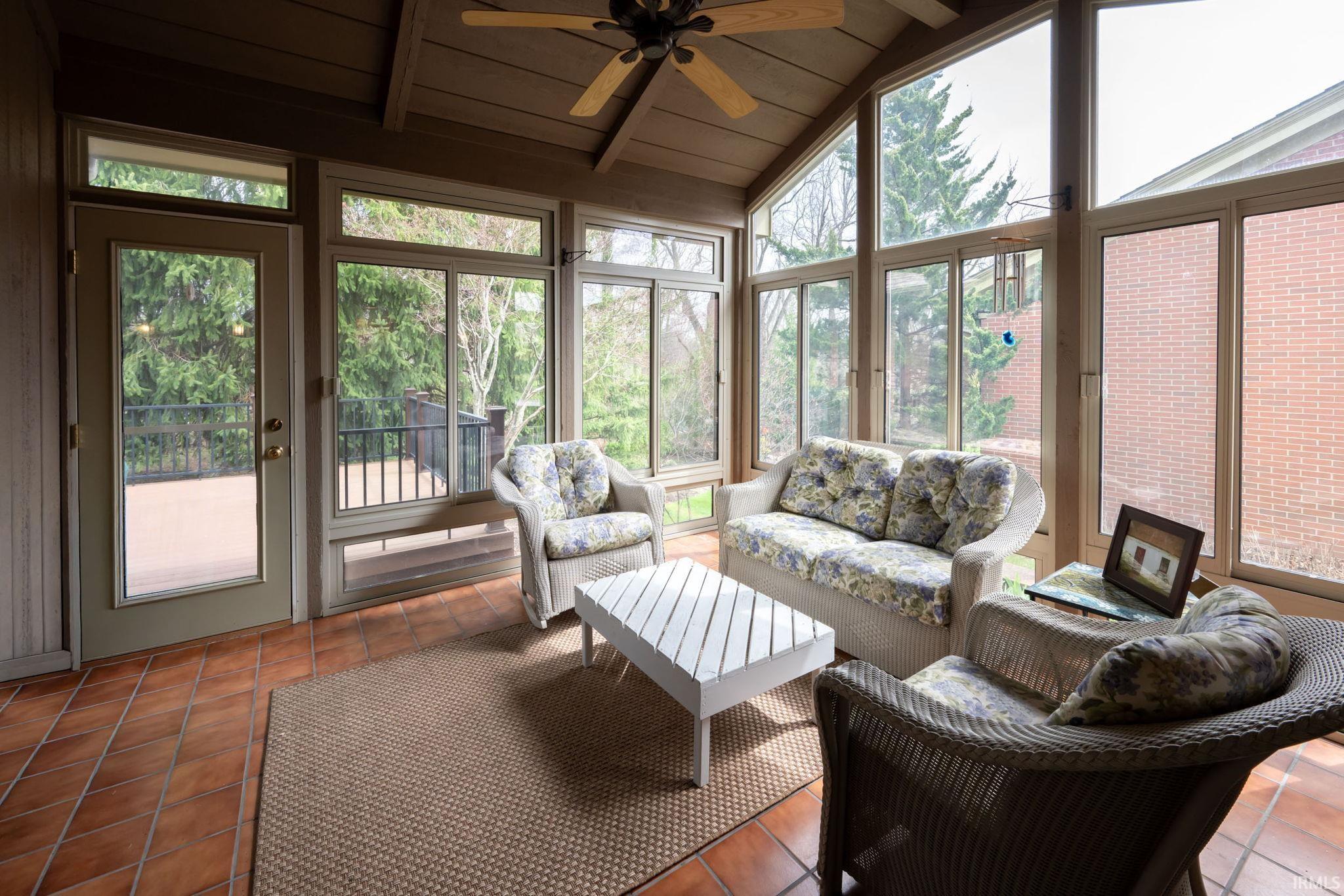 Sunroom / solarium with ceiling fan, vaulted ceiling with beams, and outdoor furniture