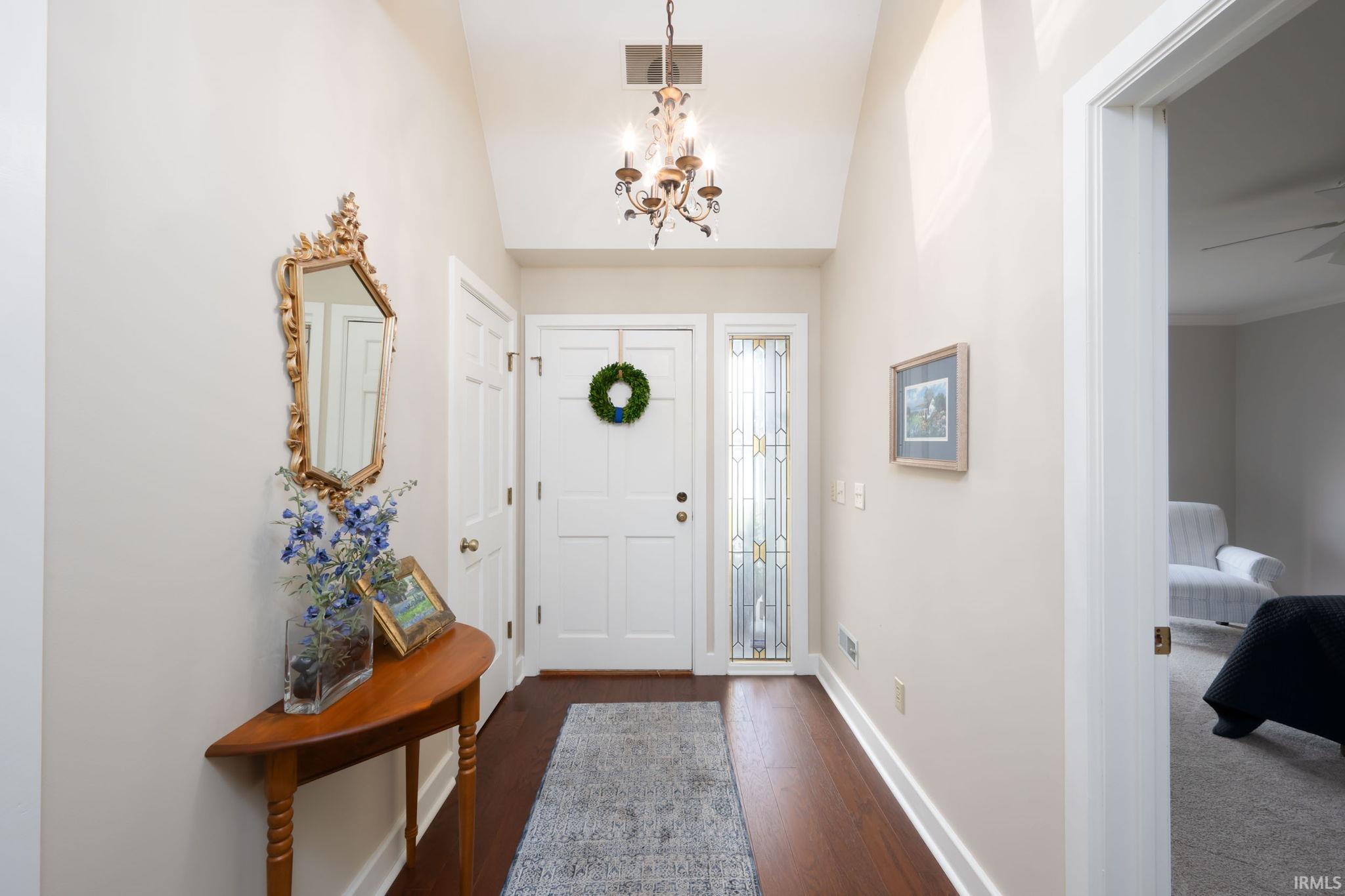 Foyer featuring lofted ceiling, dark wood-style flooring, and suspended lighting