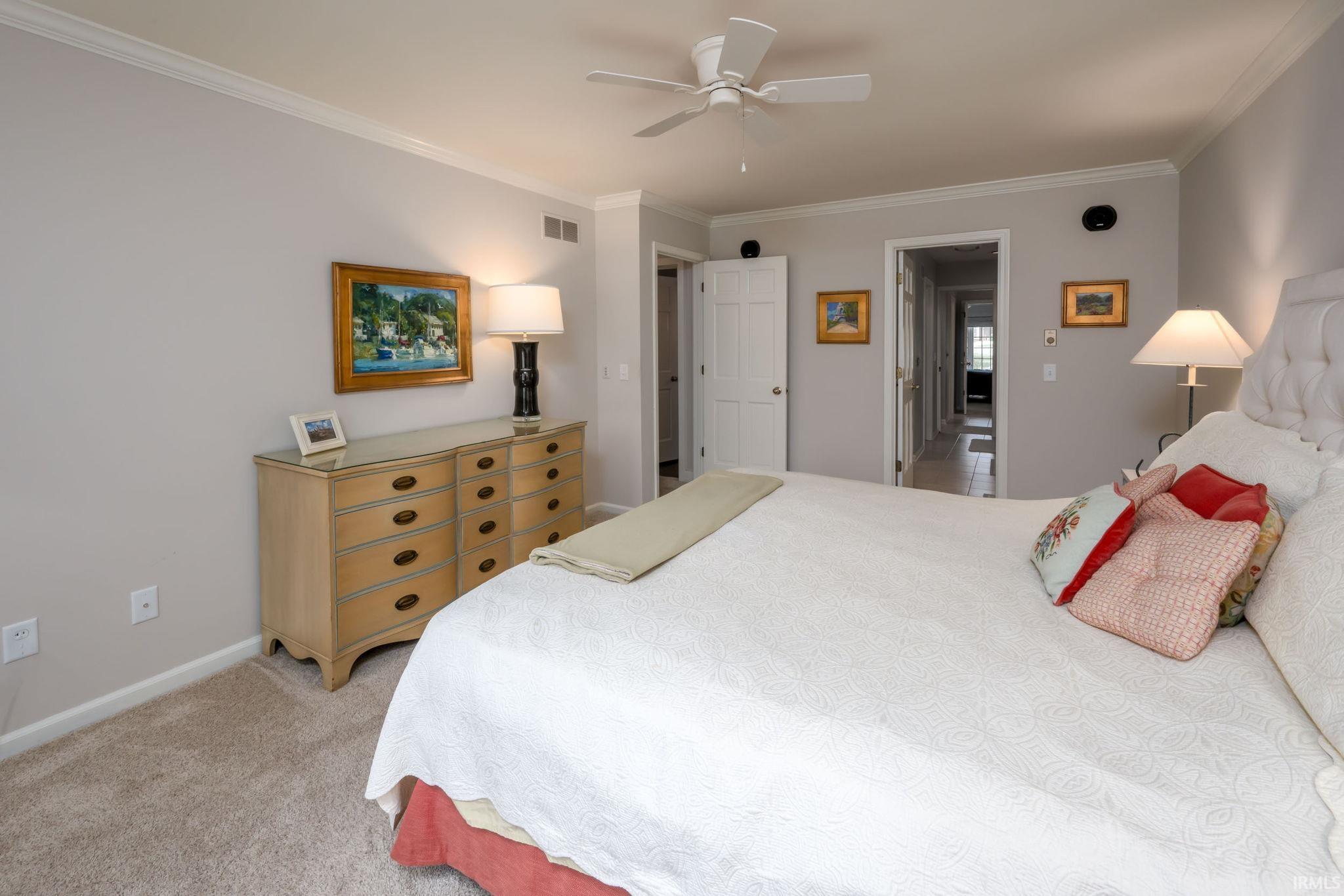 Bedroom with crown molding, light carpet, and ceiling fan