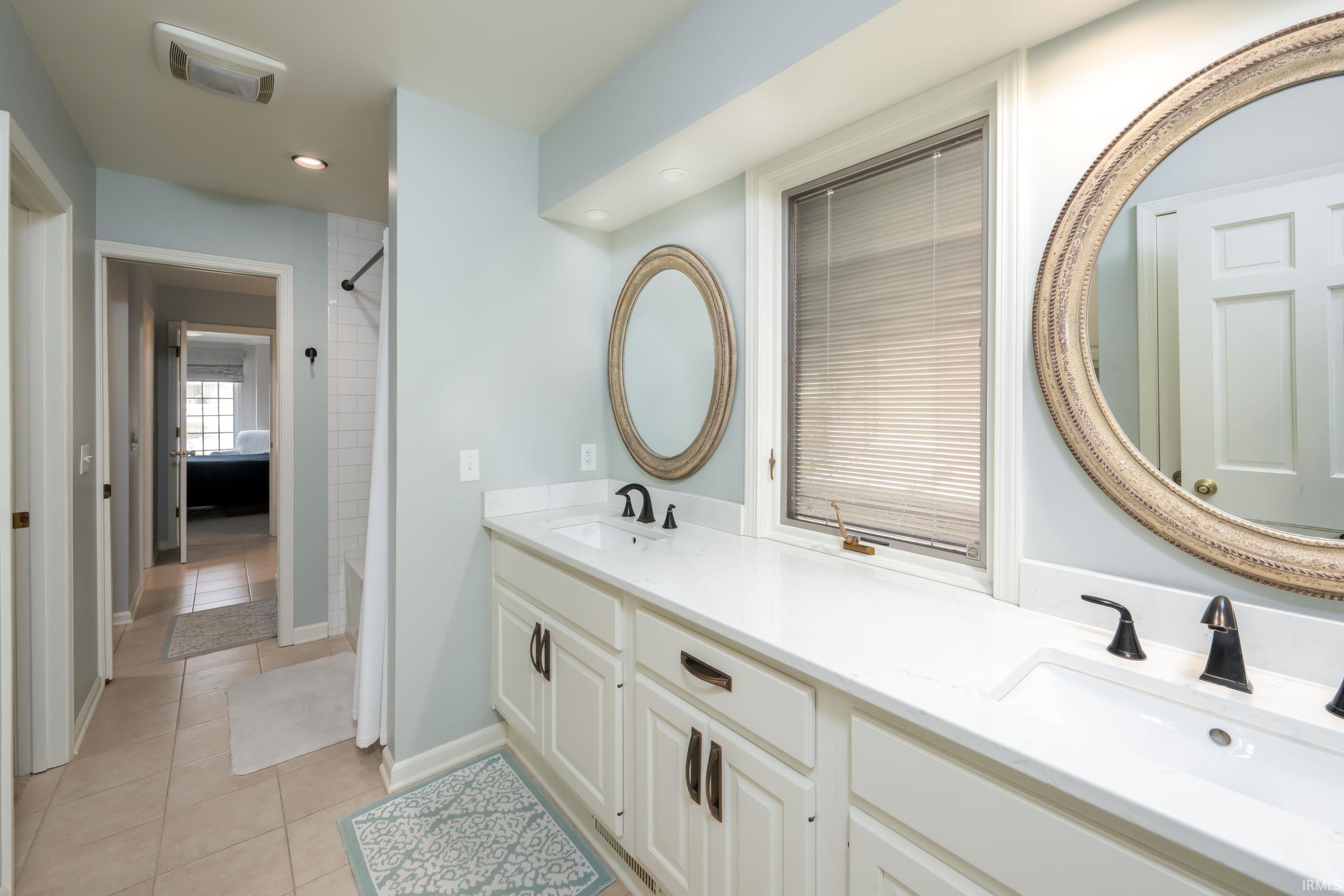 Bathroom with double vanity, light tile patterned floors, bathing tub / shower combination, and recessed lighting