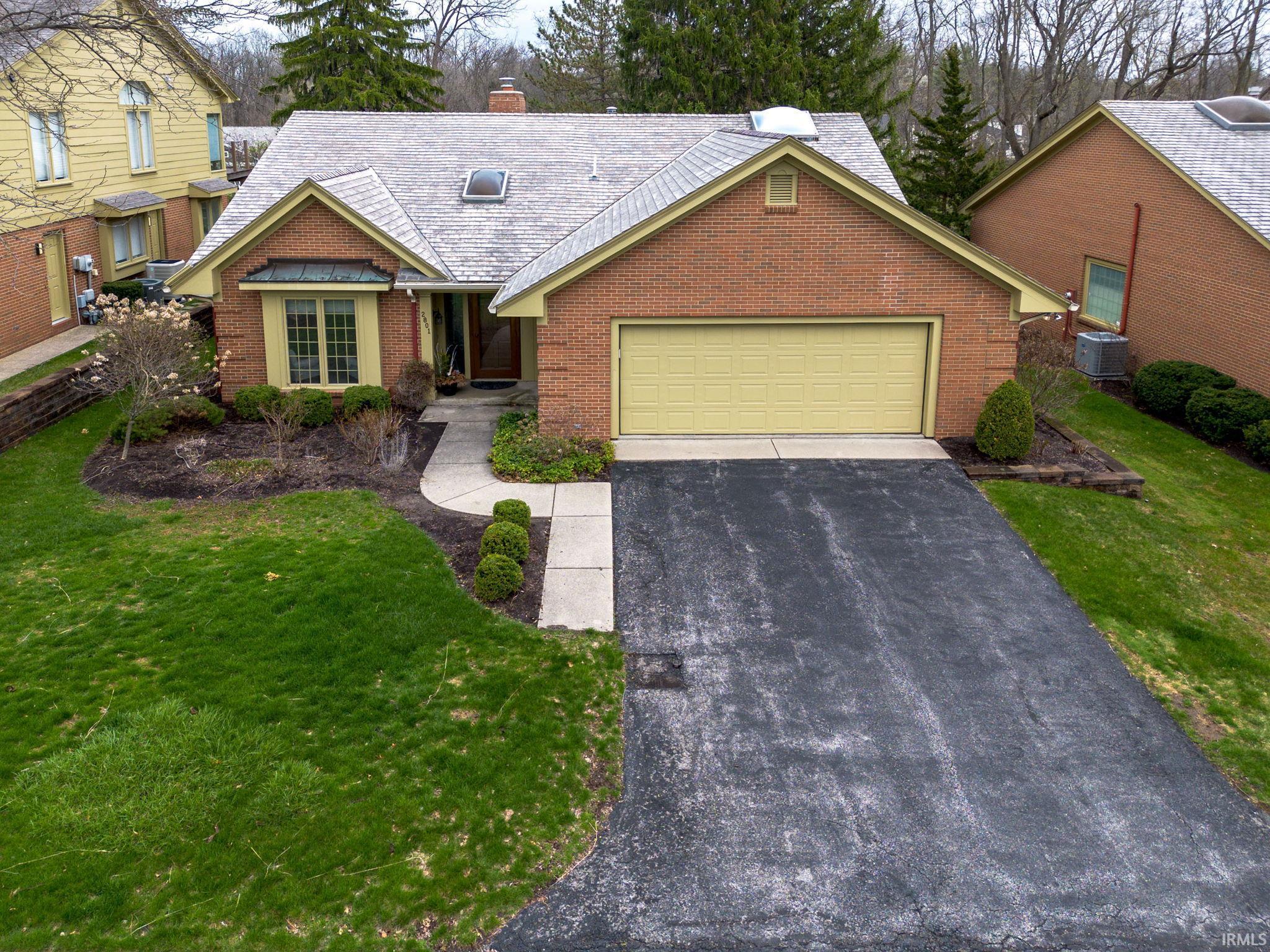 View of front of house featuring asphalt driveway, a front yard, brick siding, a garage, and a chimney