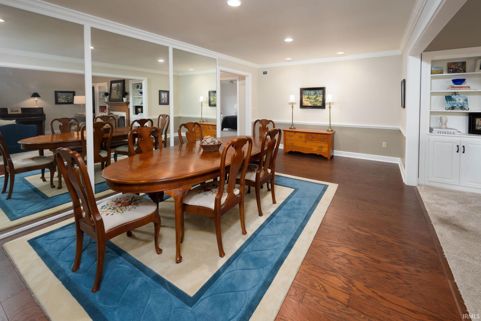 Dining room featuring built in features, dark wood-style flooring, crown molding, and recessed lighting