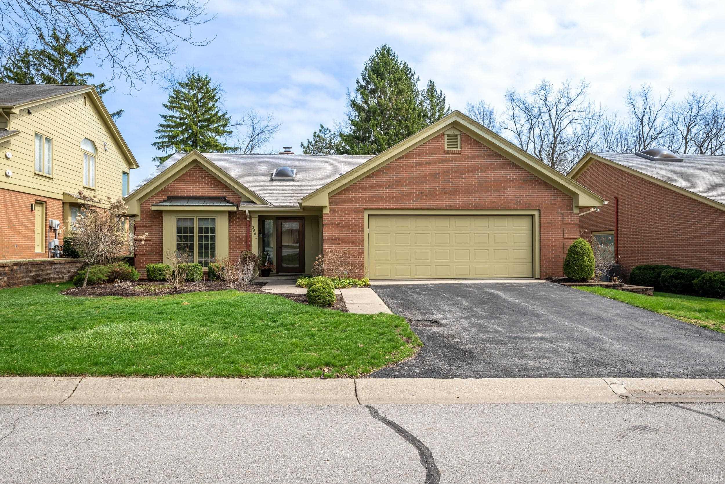 Ranch-style house with brick siding, a garage, asphalt driveway, a front lawn, and a shingled roof