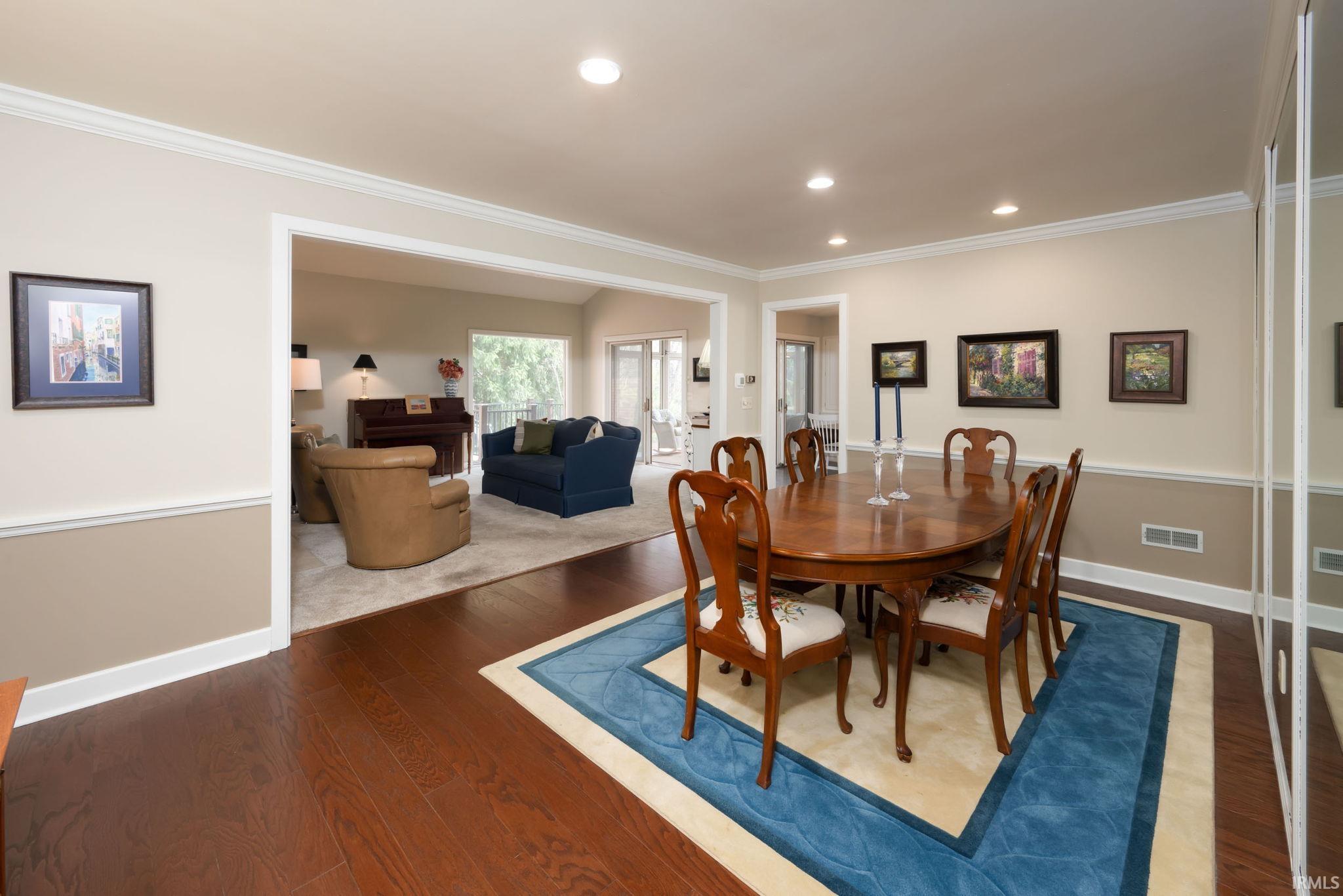 Dining space featuring dark wood-style floors, crown molding, and recessed lighting
