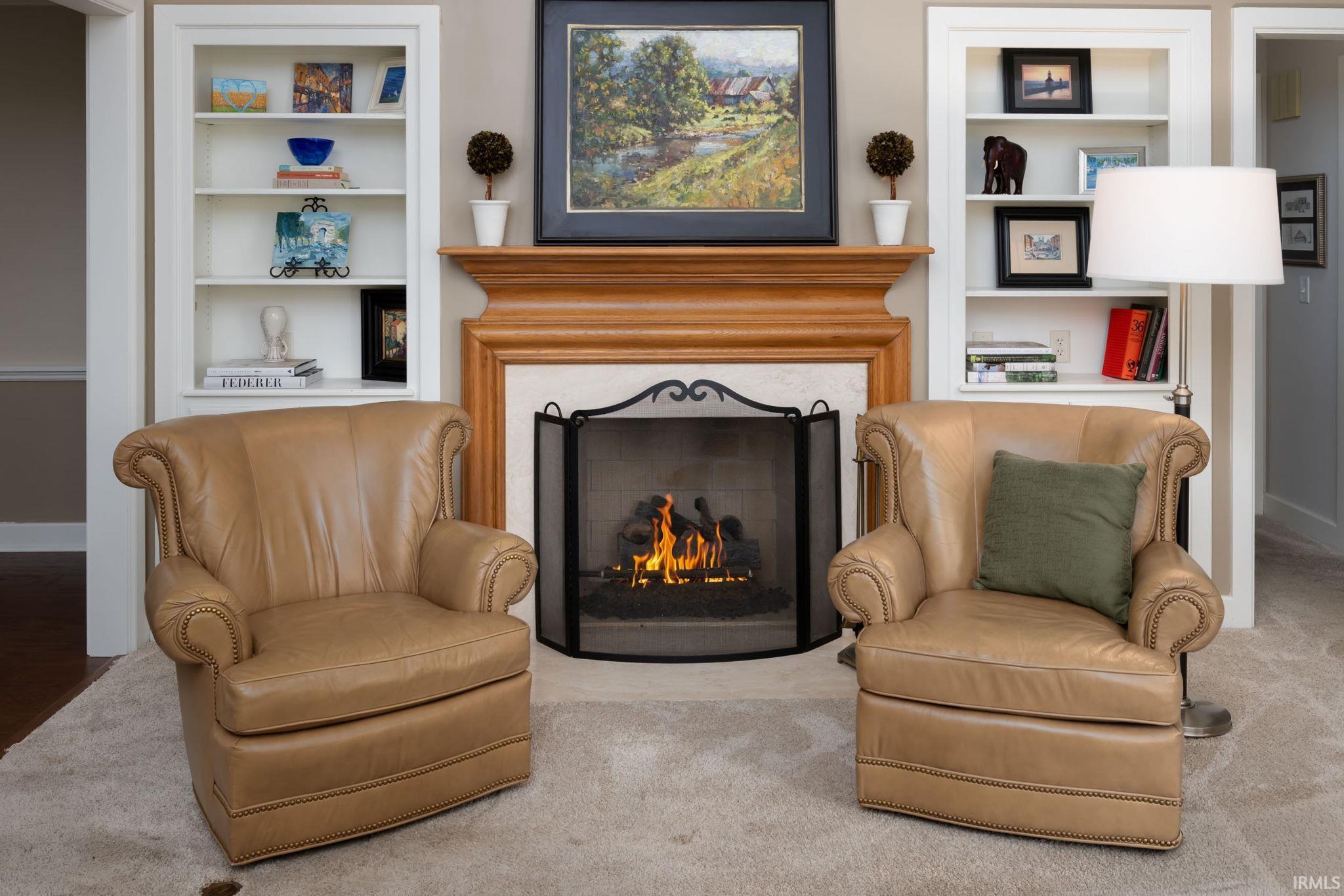 Living area with built in features, a lit fireplace, and carpet flooring