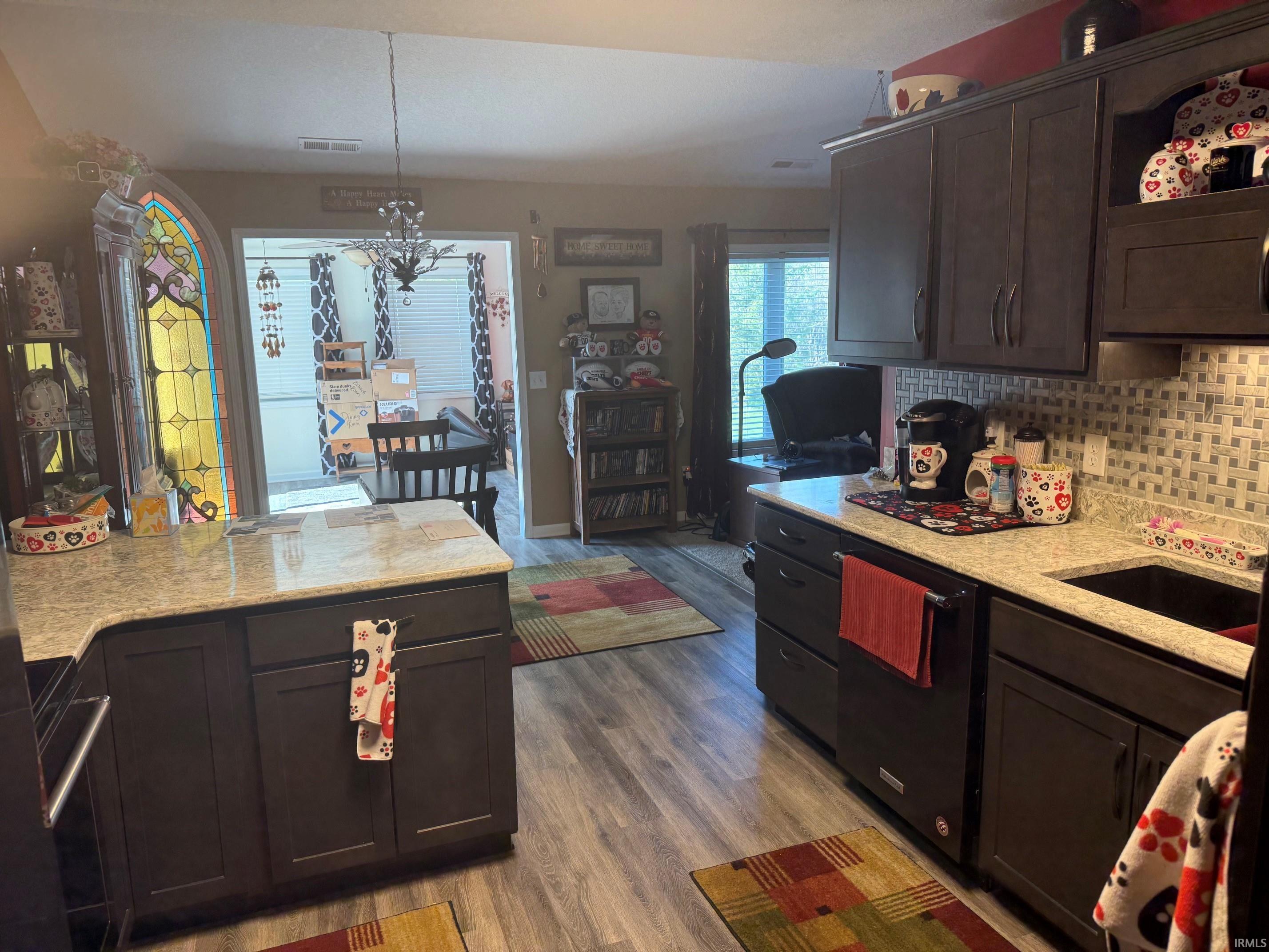 Kitchen featuring dark wood finish cabinets, light stone countertops, dishwasher, and dark wood-style flooring