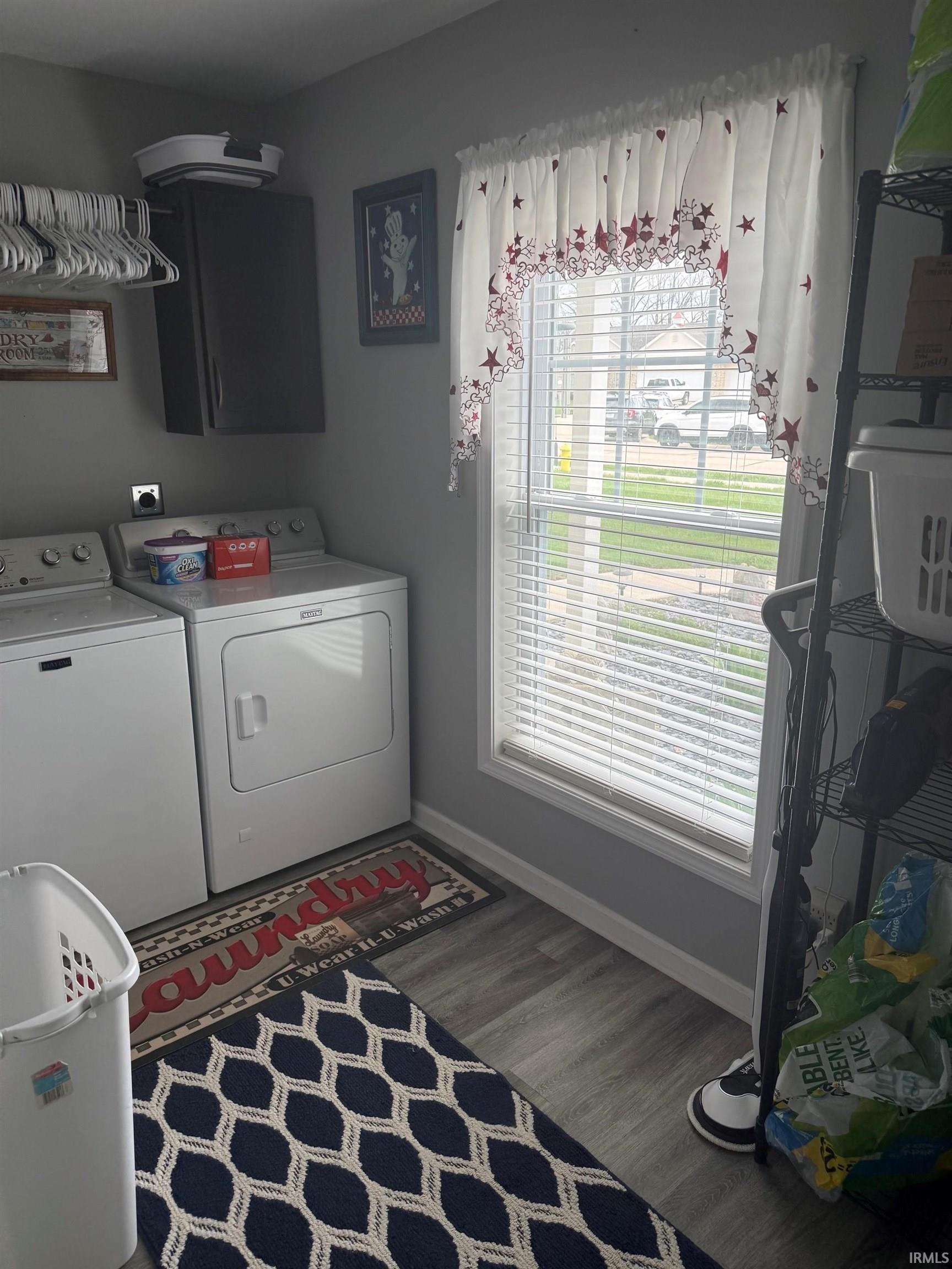 Laundry area with dark wood-type flooring, cabinet space, and washer and clothes dryer