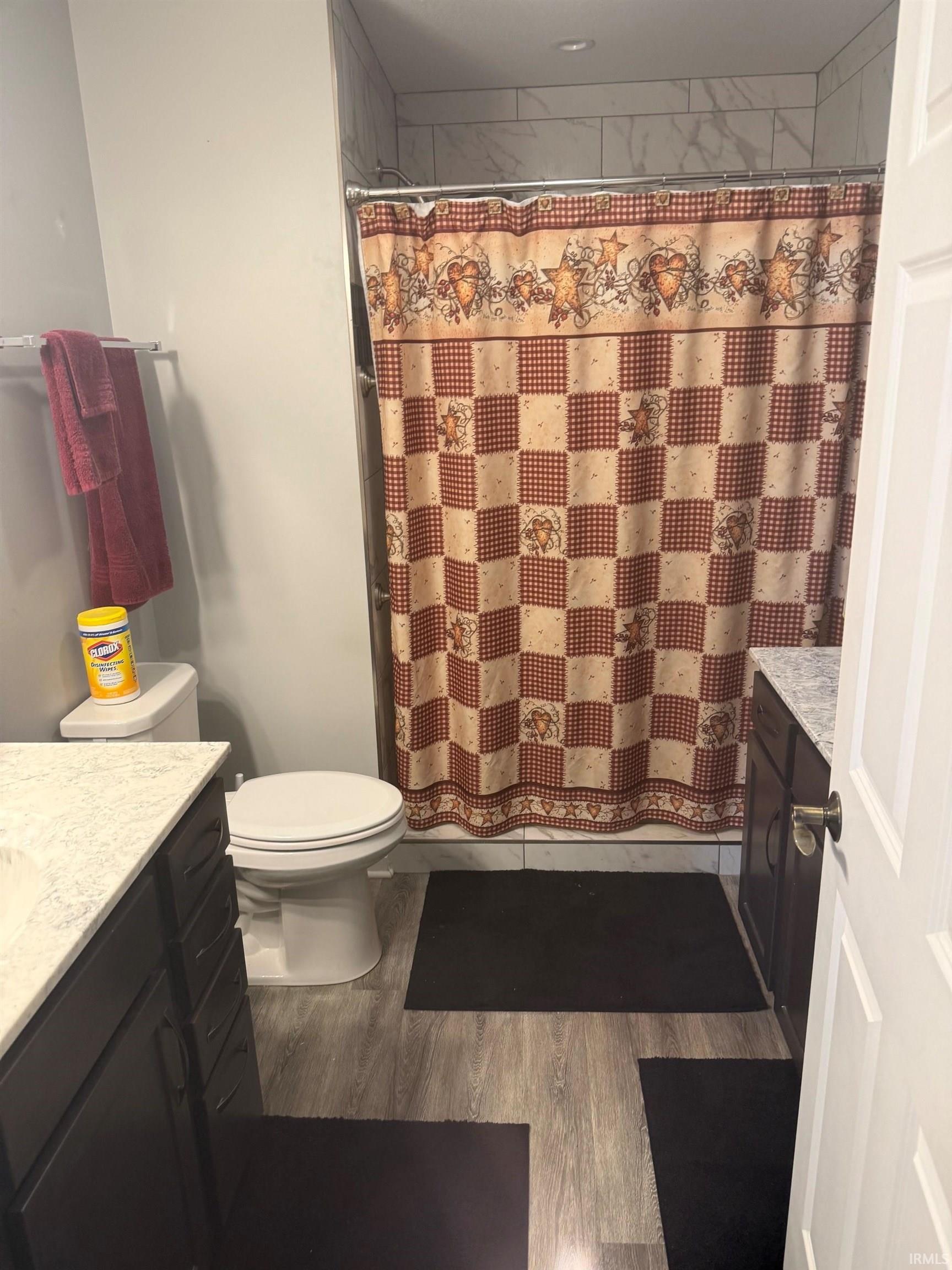 Full bathroom with vanity, a shower with shower curtain, and dark wood-style floors