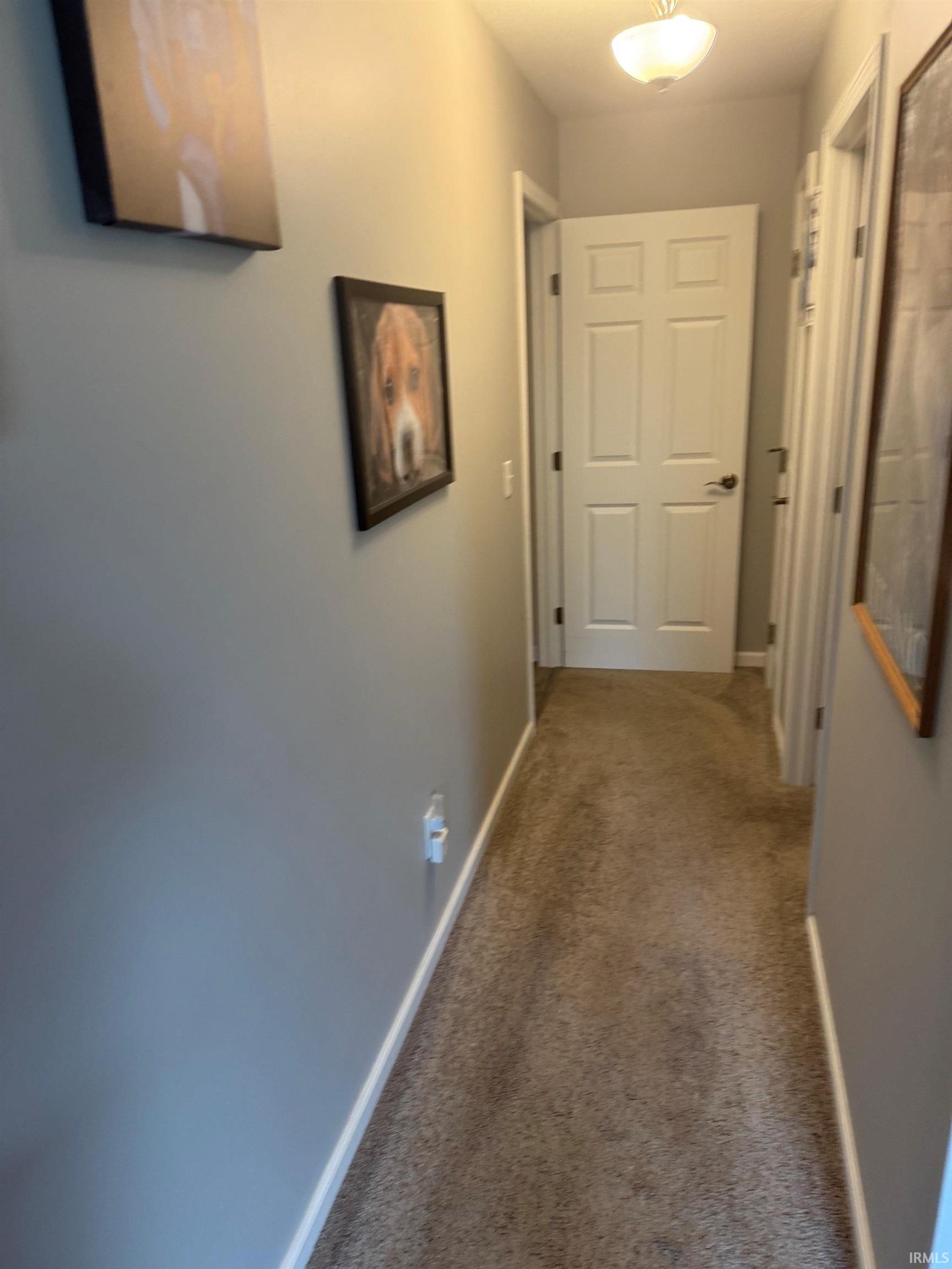 Corridor featuring dark colored carpet and baseboards