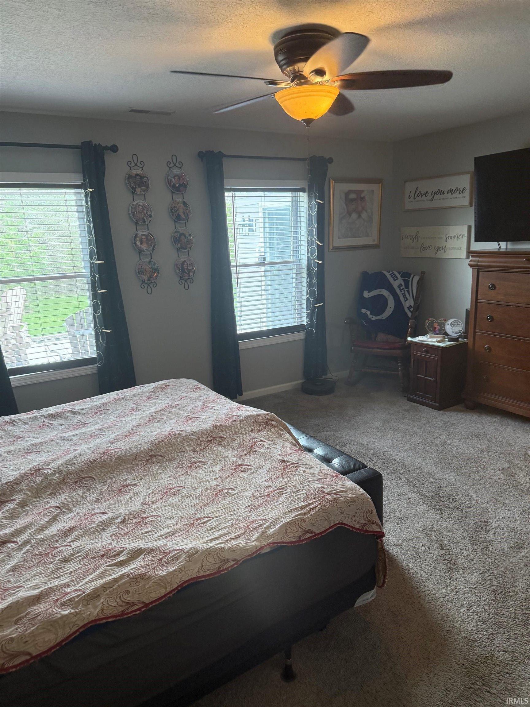 Carpeted bedroom featuring a ceiling fan and a textured ceiling