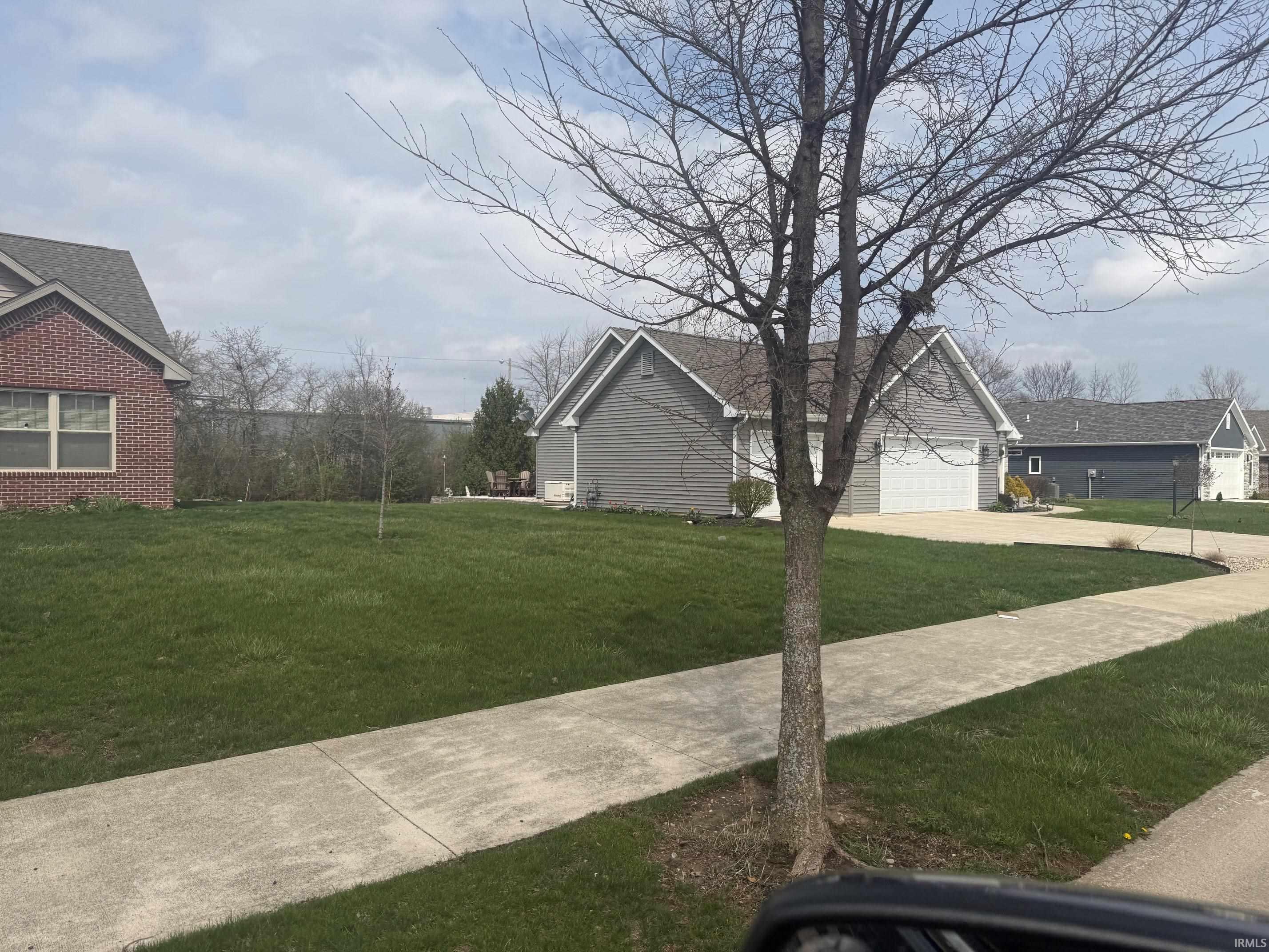 View of grassy yard with concrete driveway and an attached garage