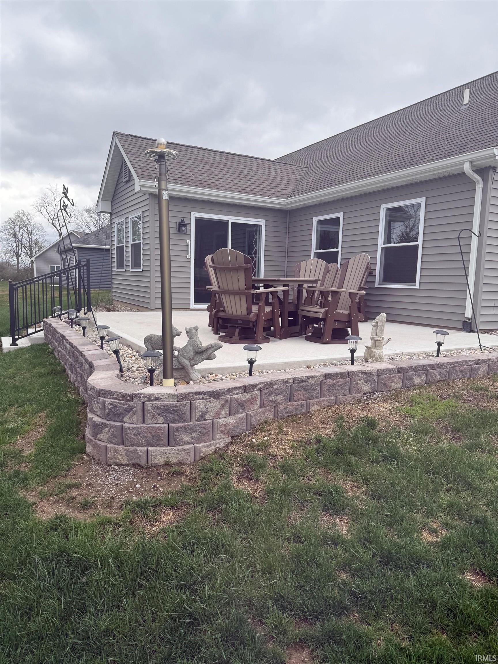 Rear view of house featuring a shingled roof, a patio area, and a yard