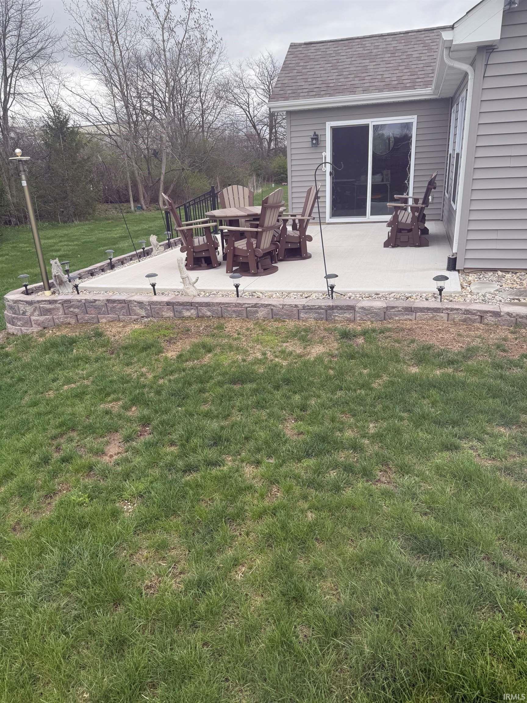 View of green lawn with a patio area and an outdoor fire pit