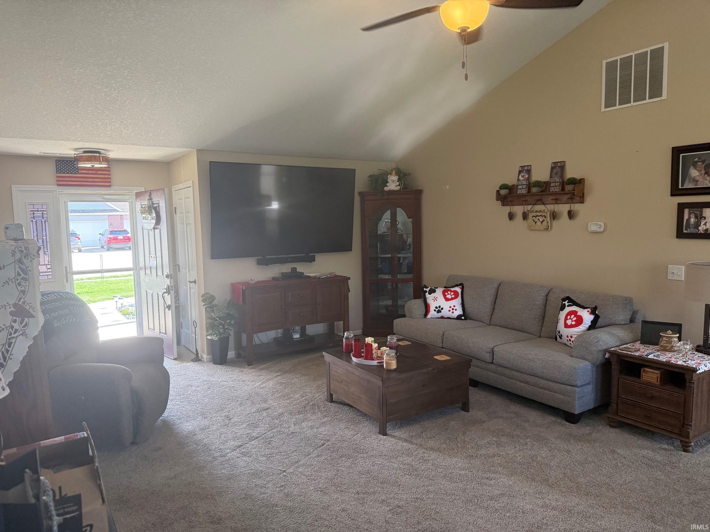 Carpeted living room featuring lofted ceiling and a ceiling fan