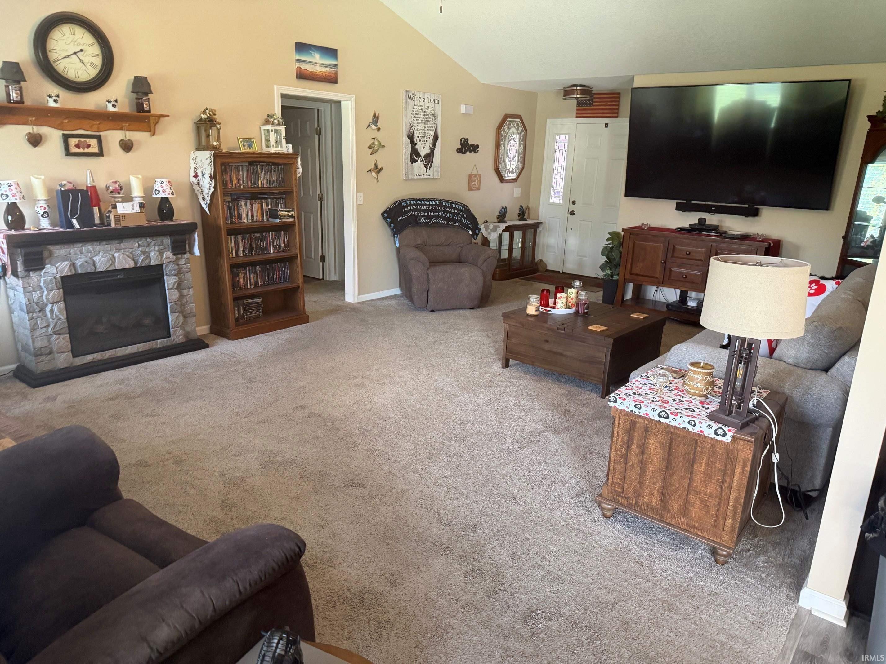 Living area featuring a fireplace, vaulted ceiling, and light carpet