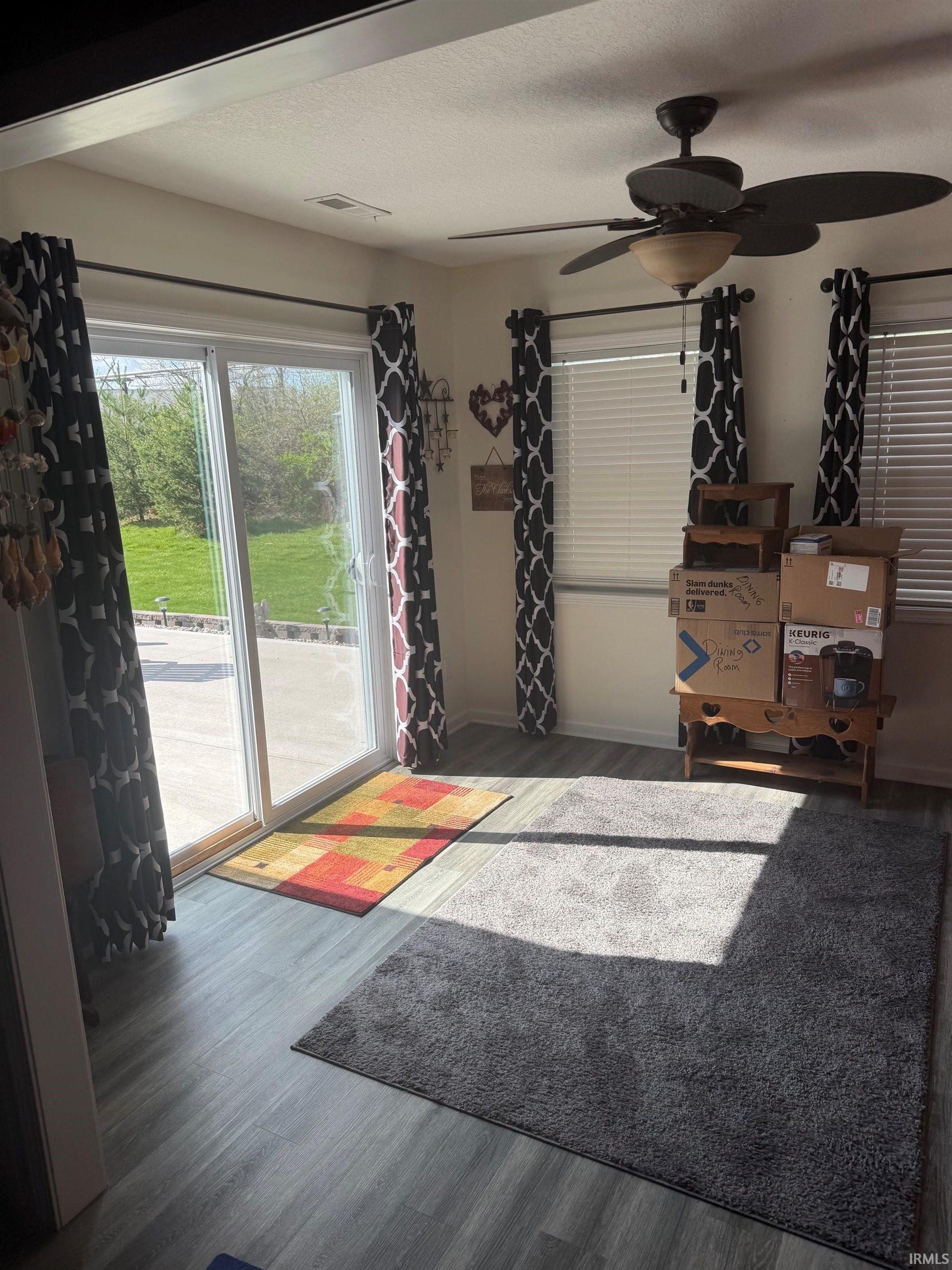 Living room featuring dark wood-type flooring, a ceiling fan, and a textured ceiling