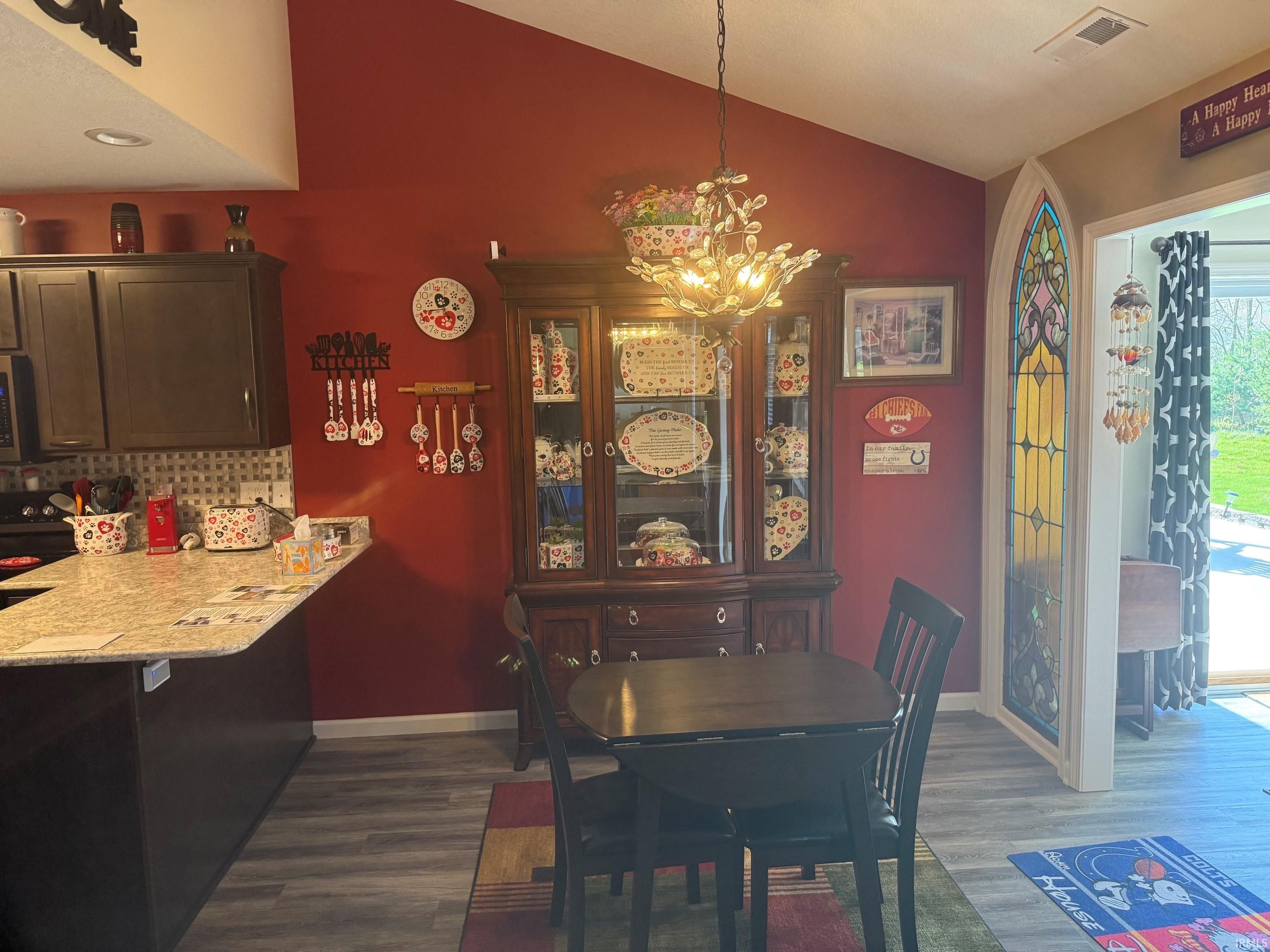 Dining space with vaulted ceiling, hanging lights, and dark wood-style floors