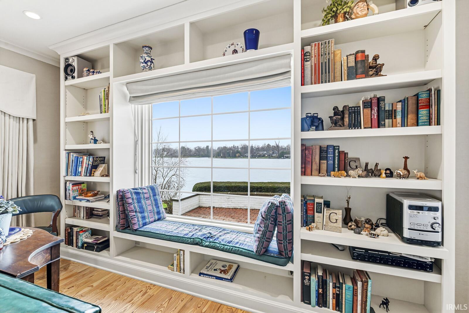 Living area with crown molding, a water view, and light wood-type flooring