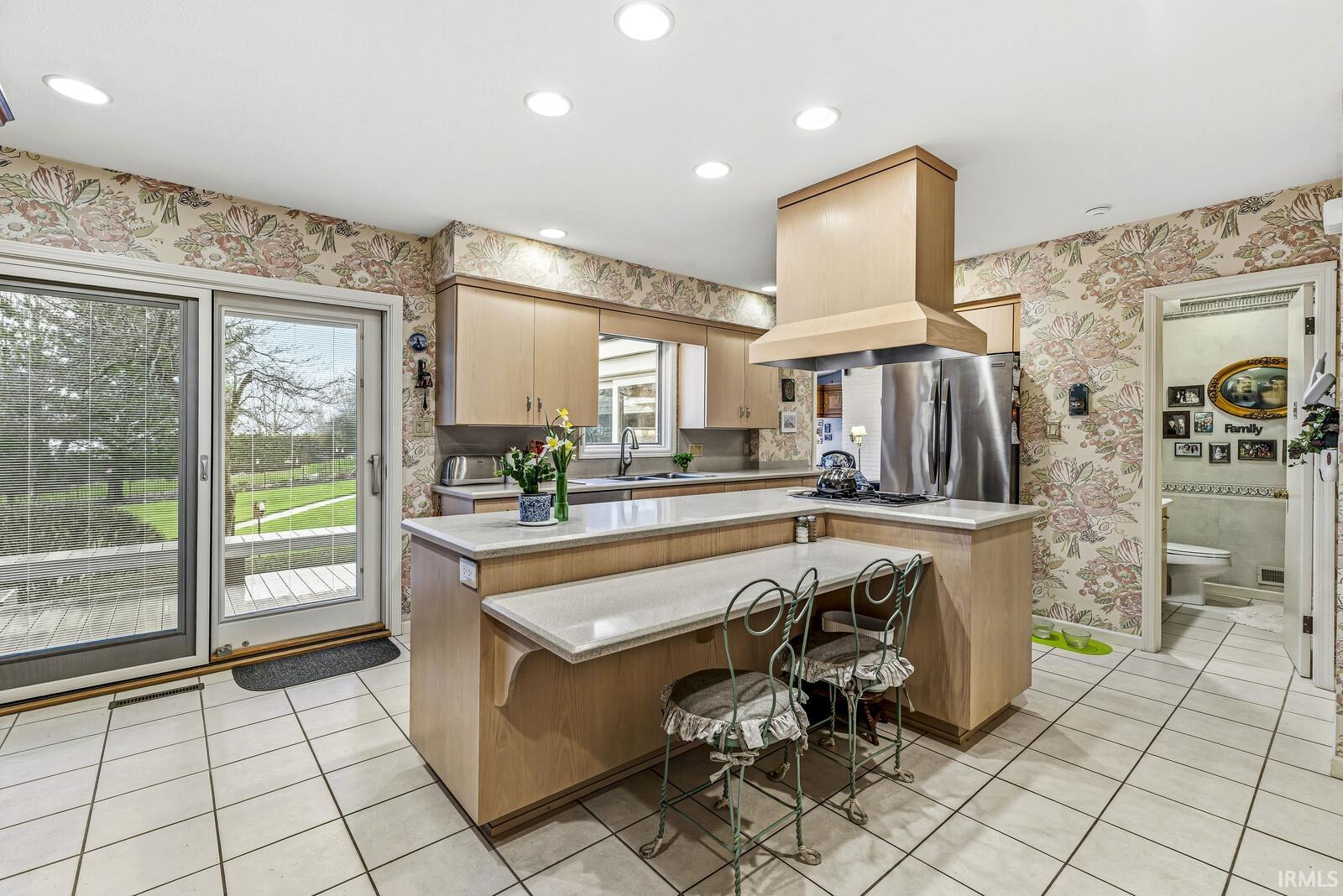 Kitchen featuring a kitchen bar, a kitchen island, light tile patterned floors, light wood finish cabinetry, and recessed lighting