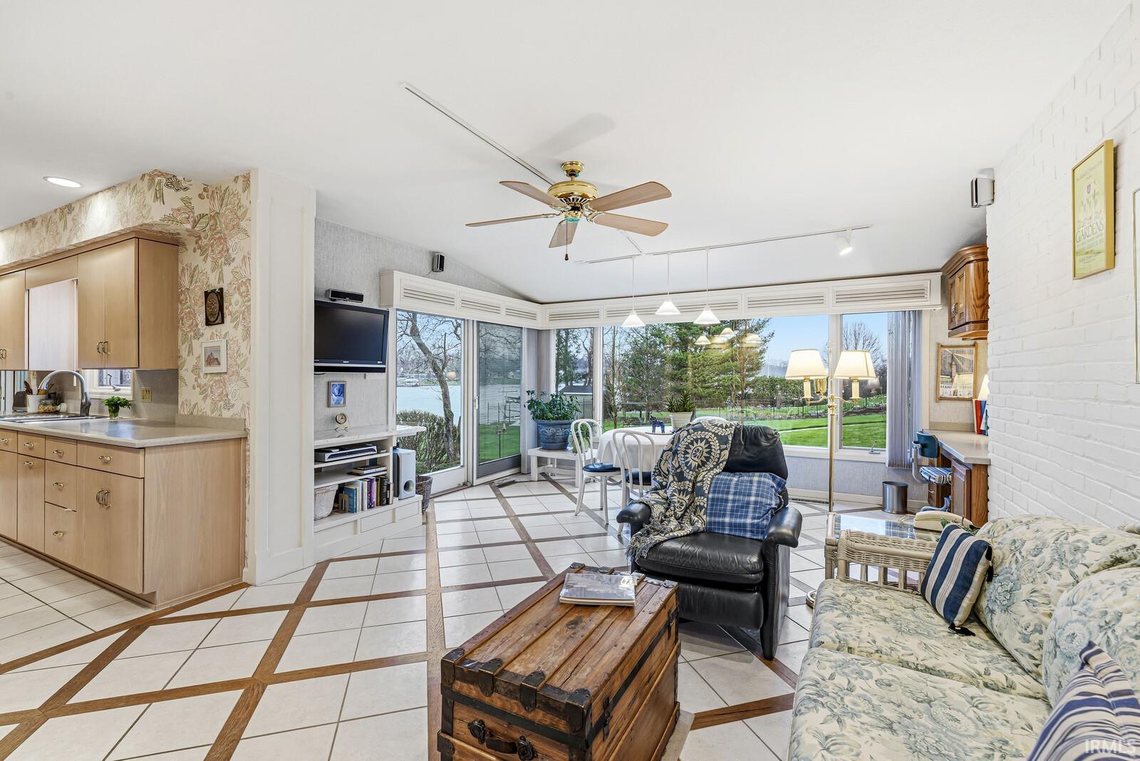 Living room featuring wallpapered walls, ceiling fan, vaulted ceiling, and inlaid floor details