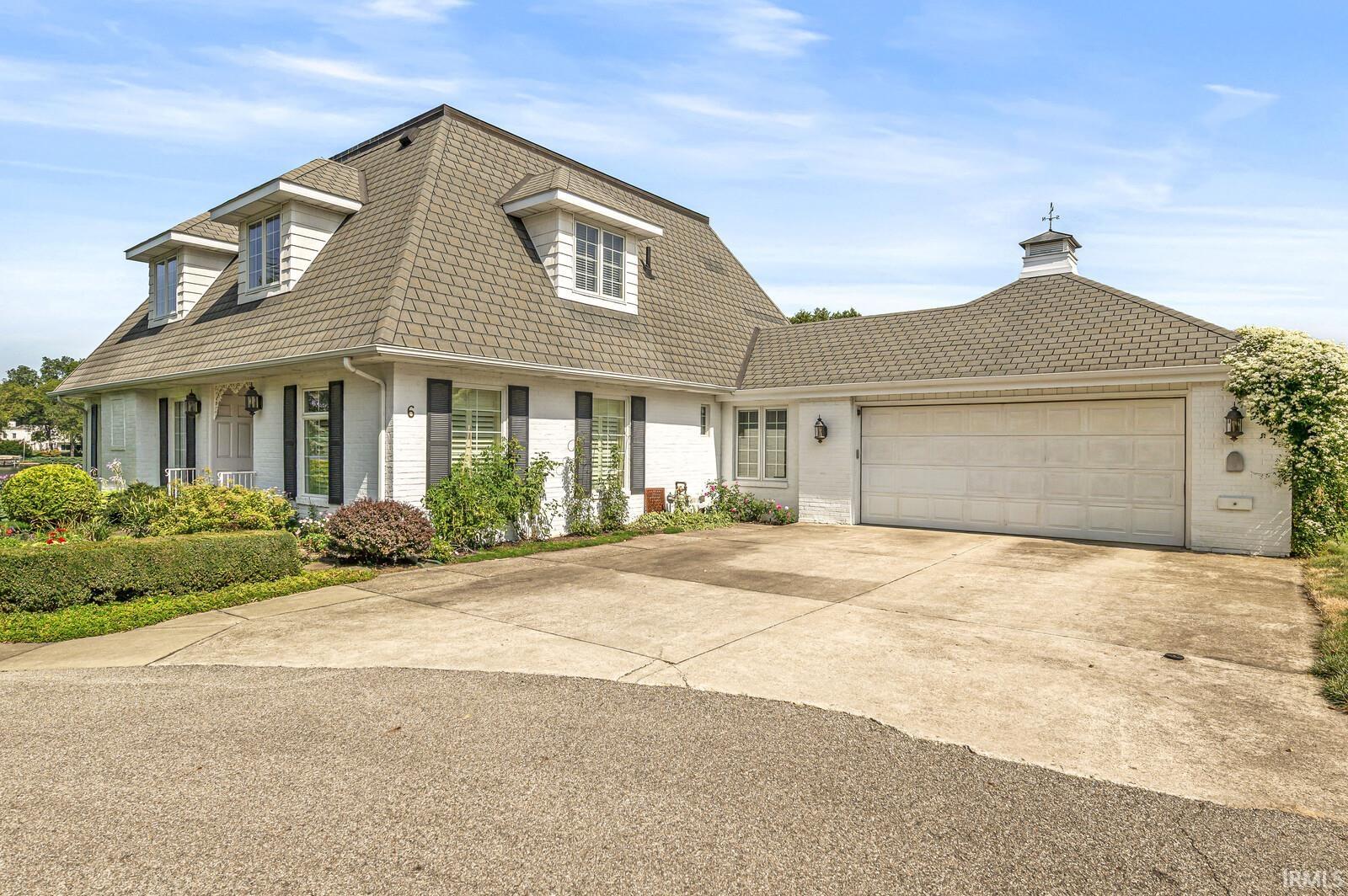 View of front of home with driveway, brick siding, a garage, and roof with shingles