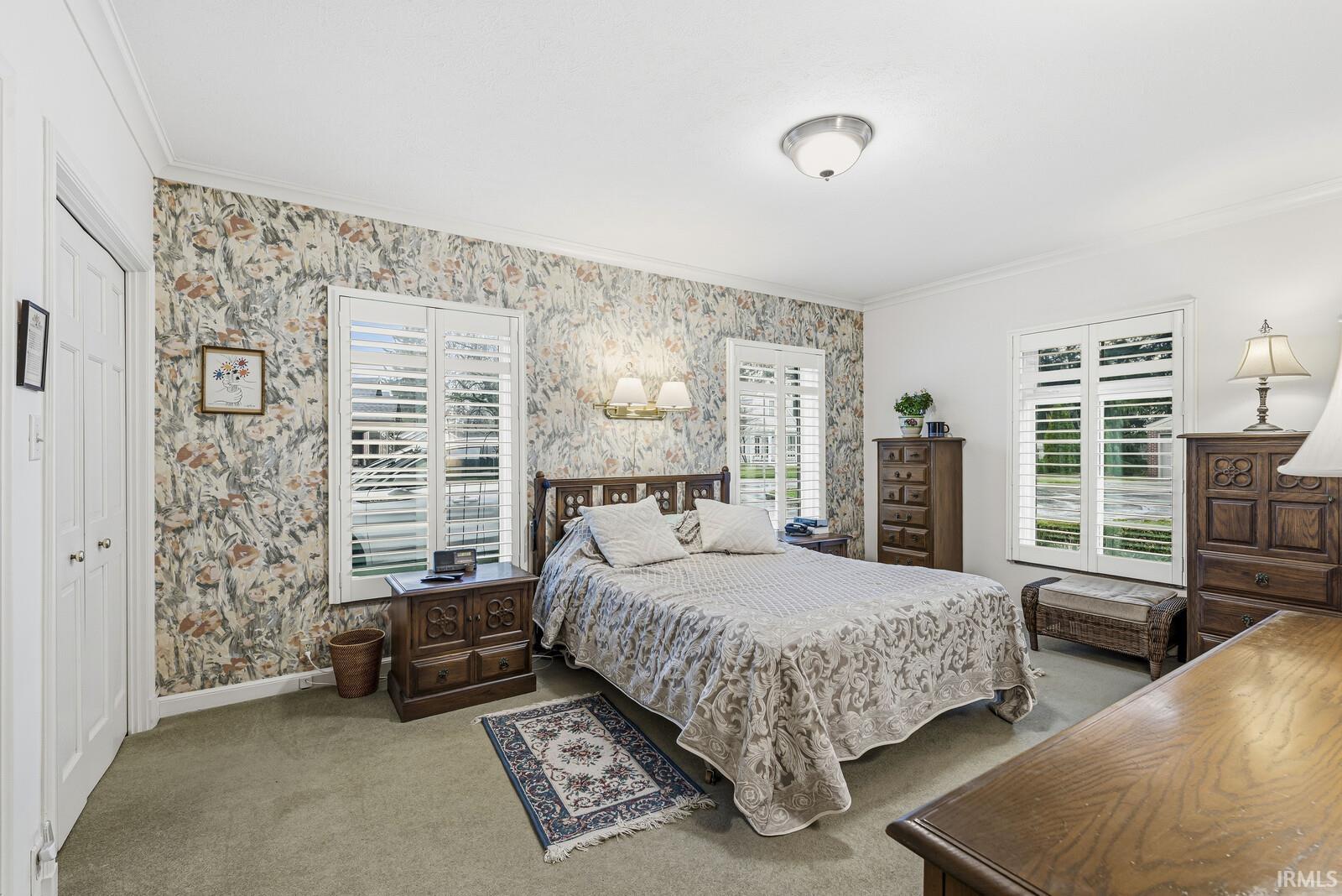 Bedroom featuring ornamental molding, carpet, wallpapered walls, and a closet