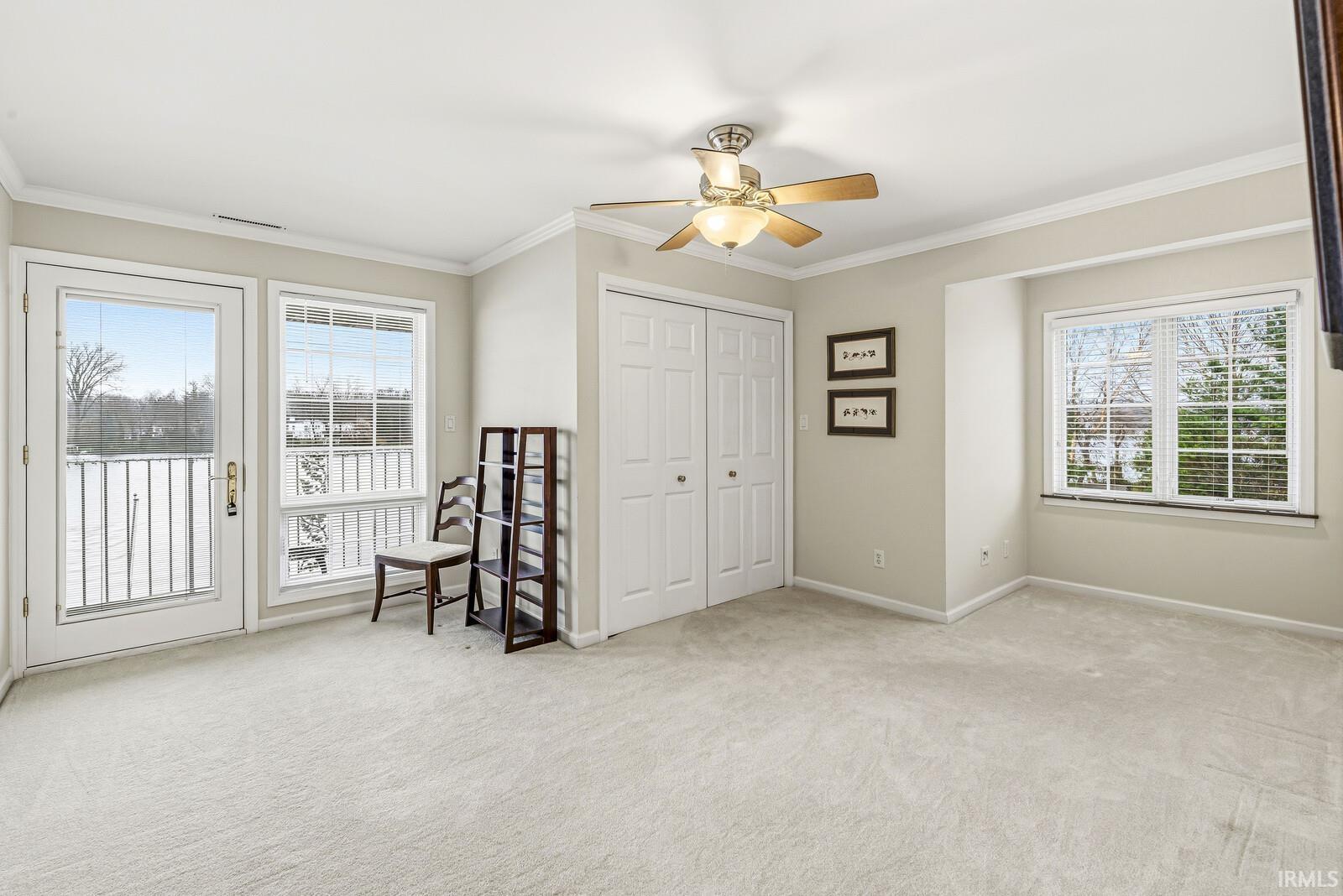 Unfurnished bedroom with light carpet, ornamental molding, access to exterior, a ceiling fan, and a closet