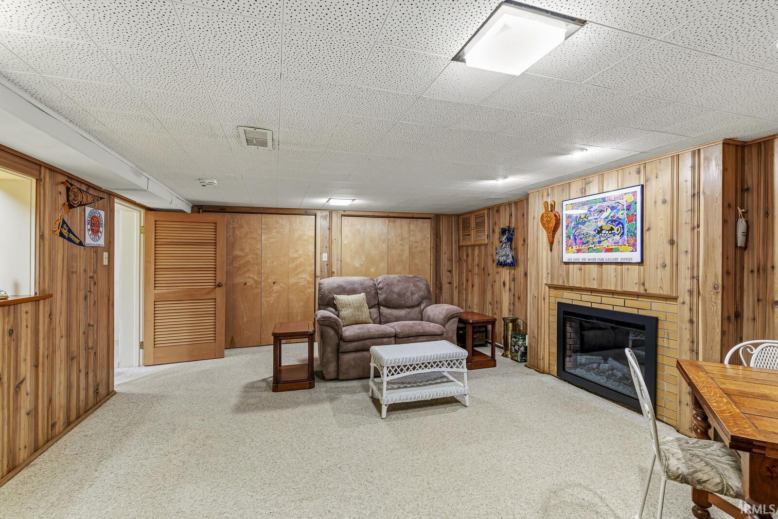 Living area with a fireplace, wood walls, and carpet floors