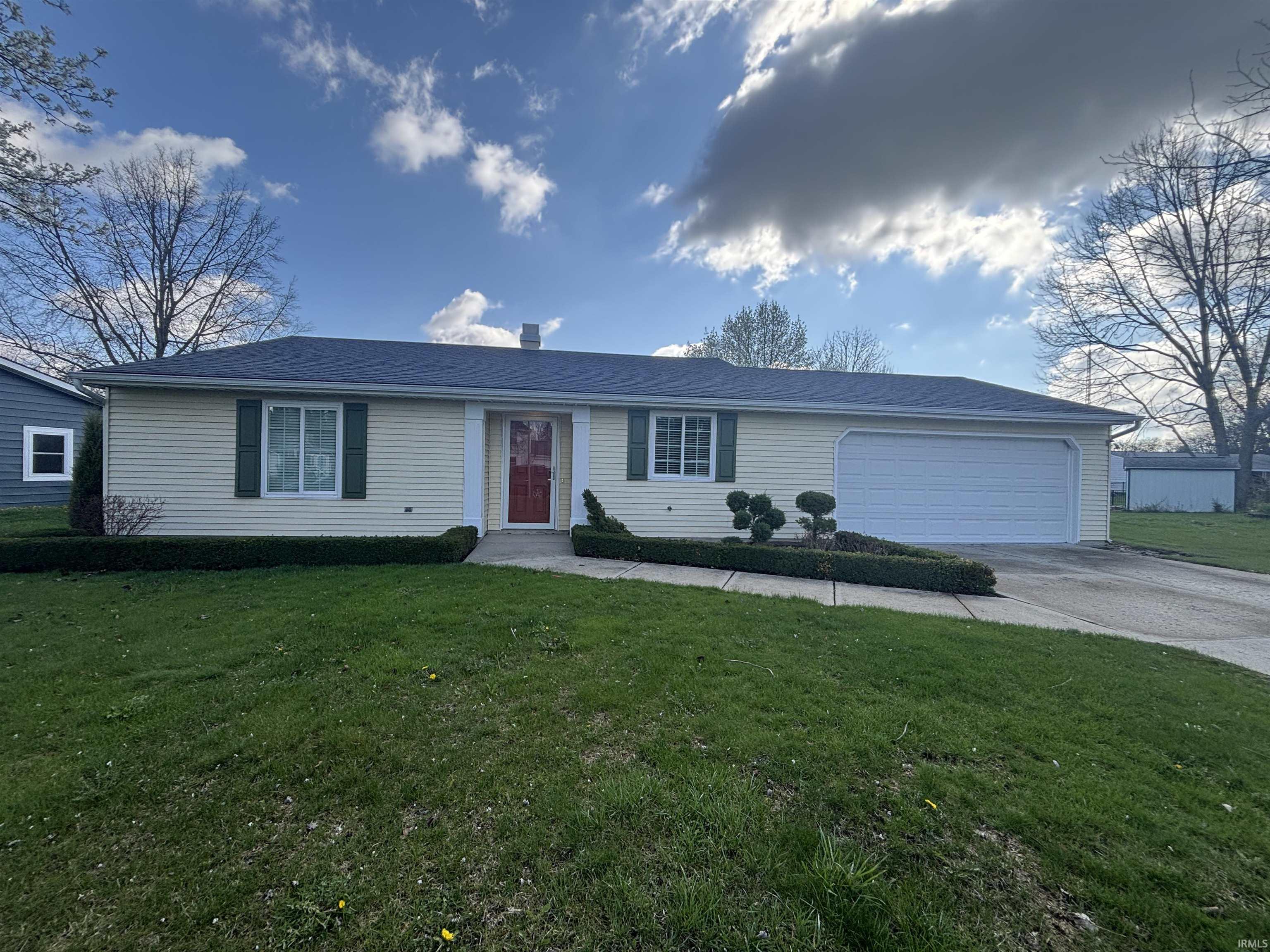 Ranch-style house with a front lawn, an attached garage, and driveway