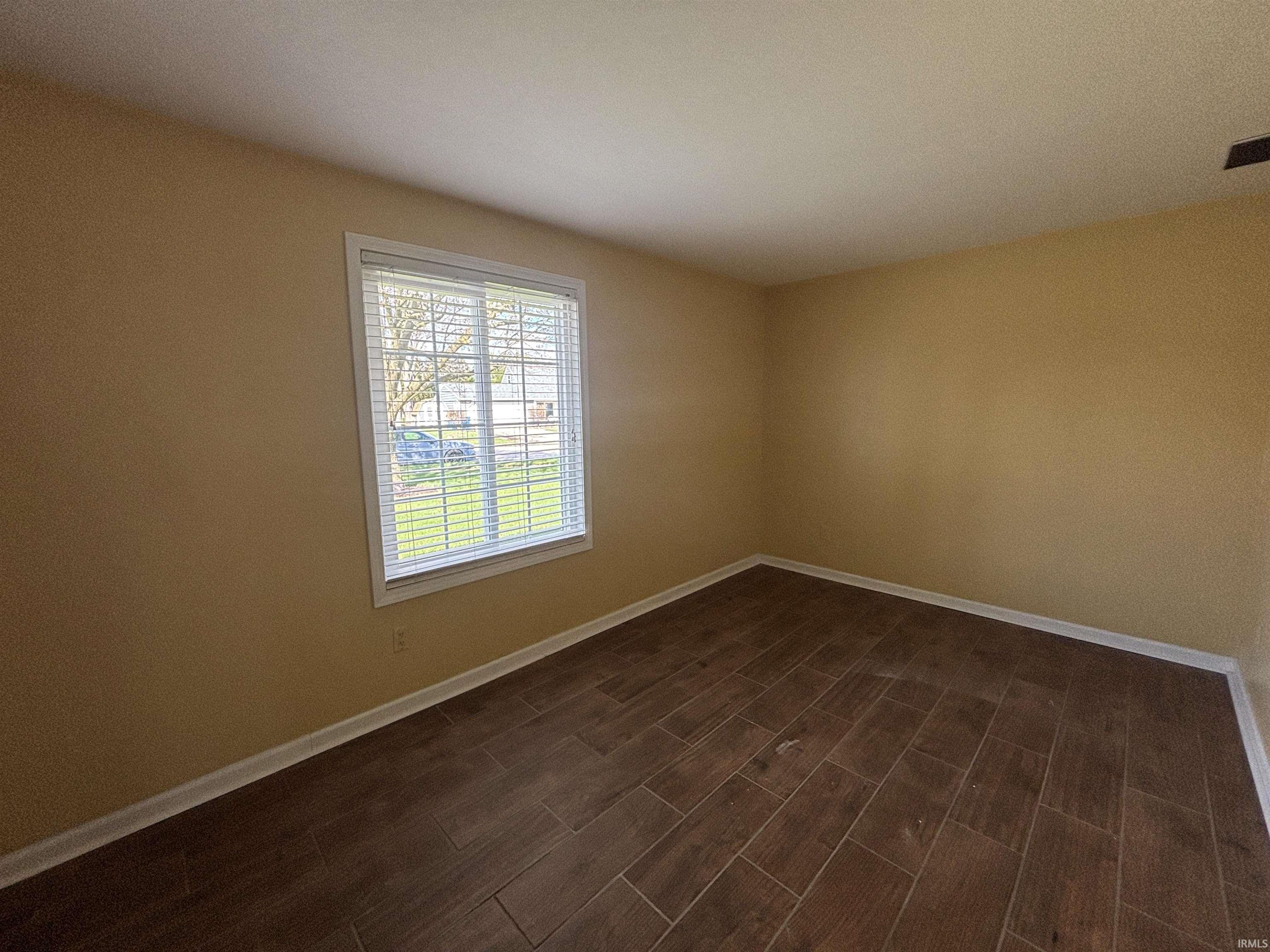 Spare room featuring baseboards and wood tiled floors