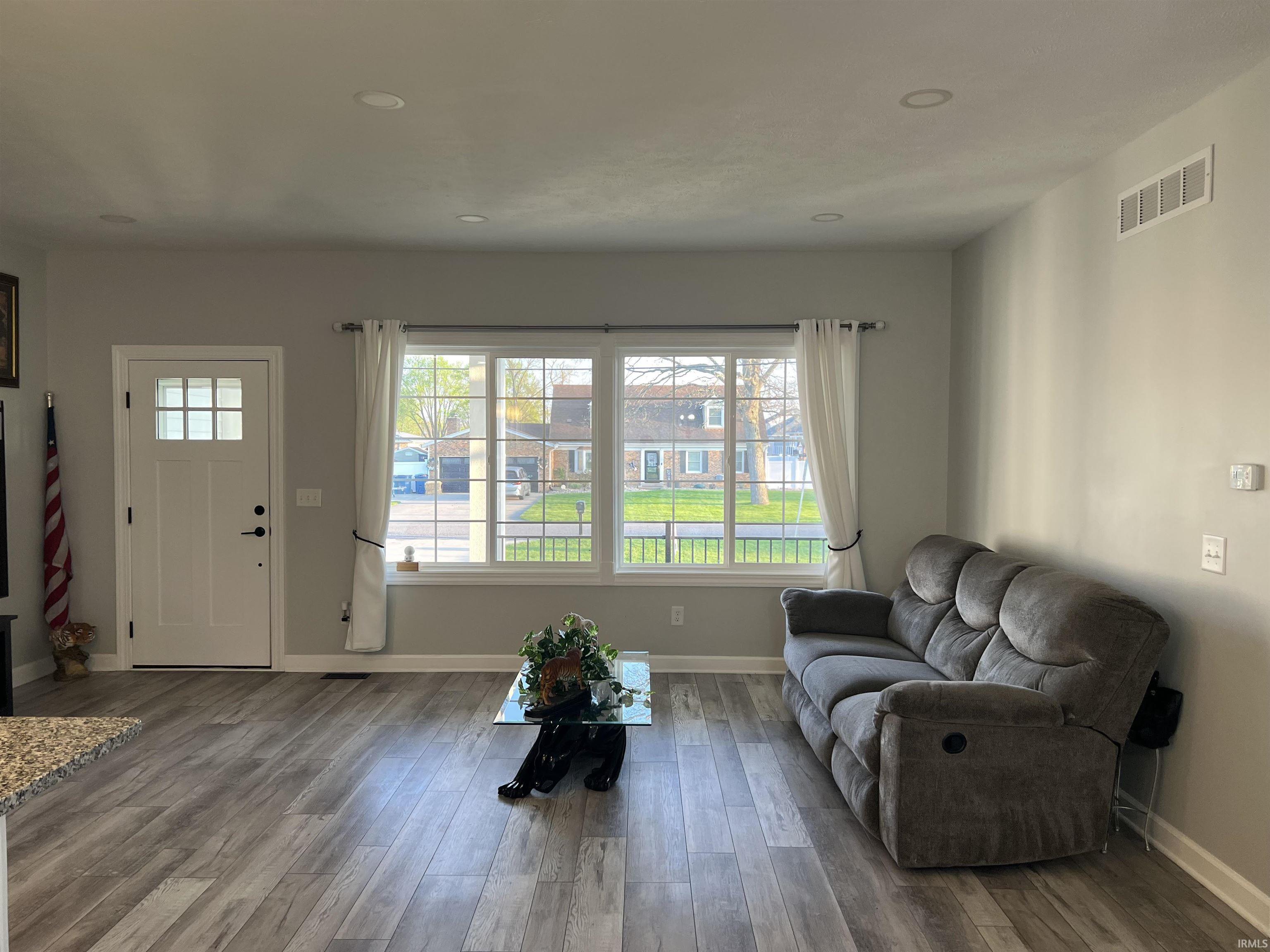 Spacious interior featuring wood-finish flooring, light gray wall tones, and recessed ceiling lighting