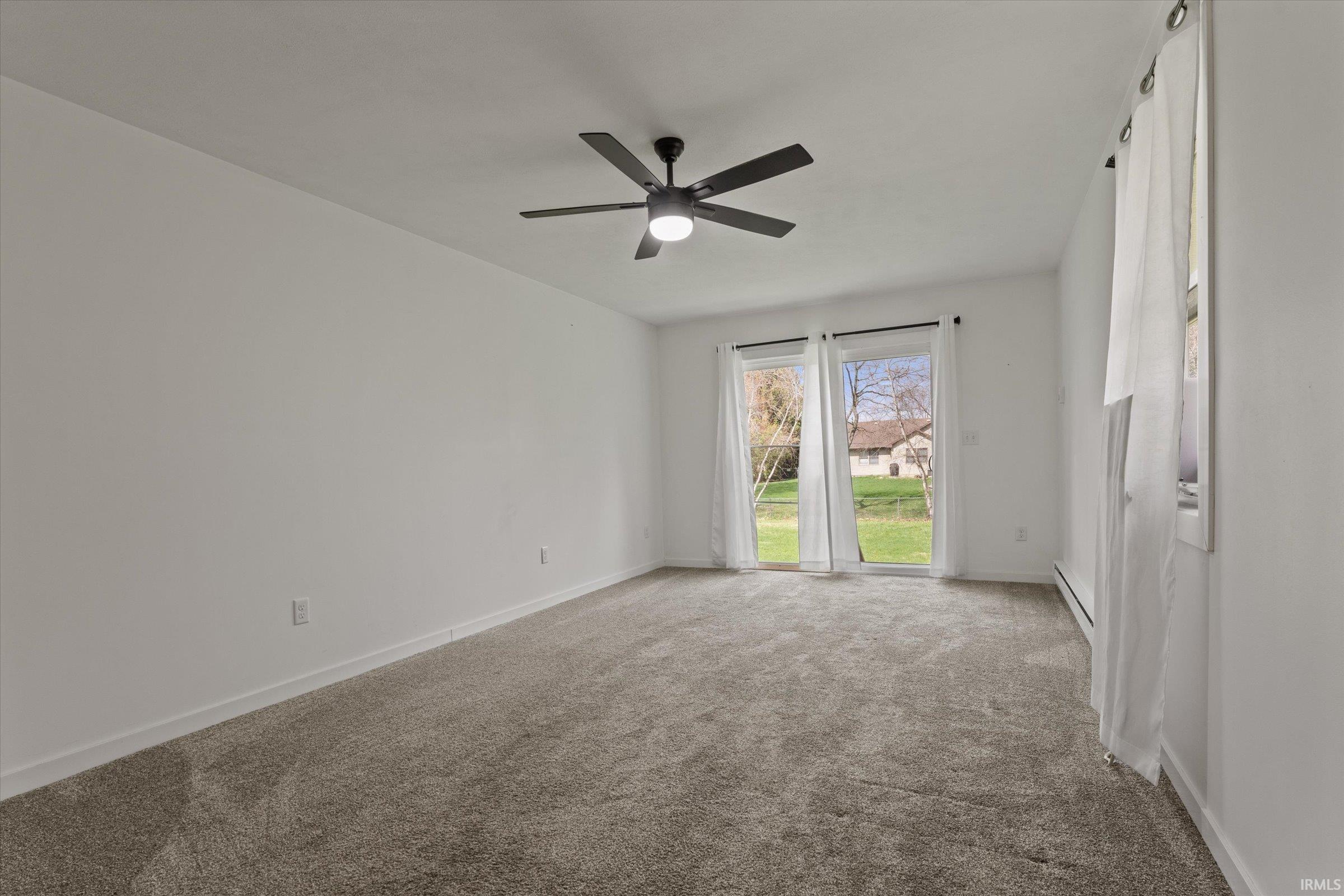 Spare room with carpet, baseboard heating, and a ceiling fan