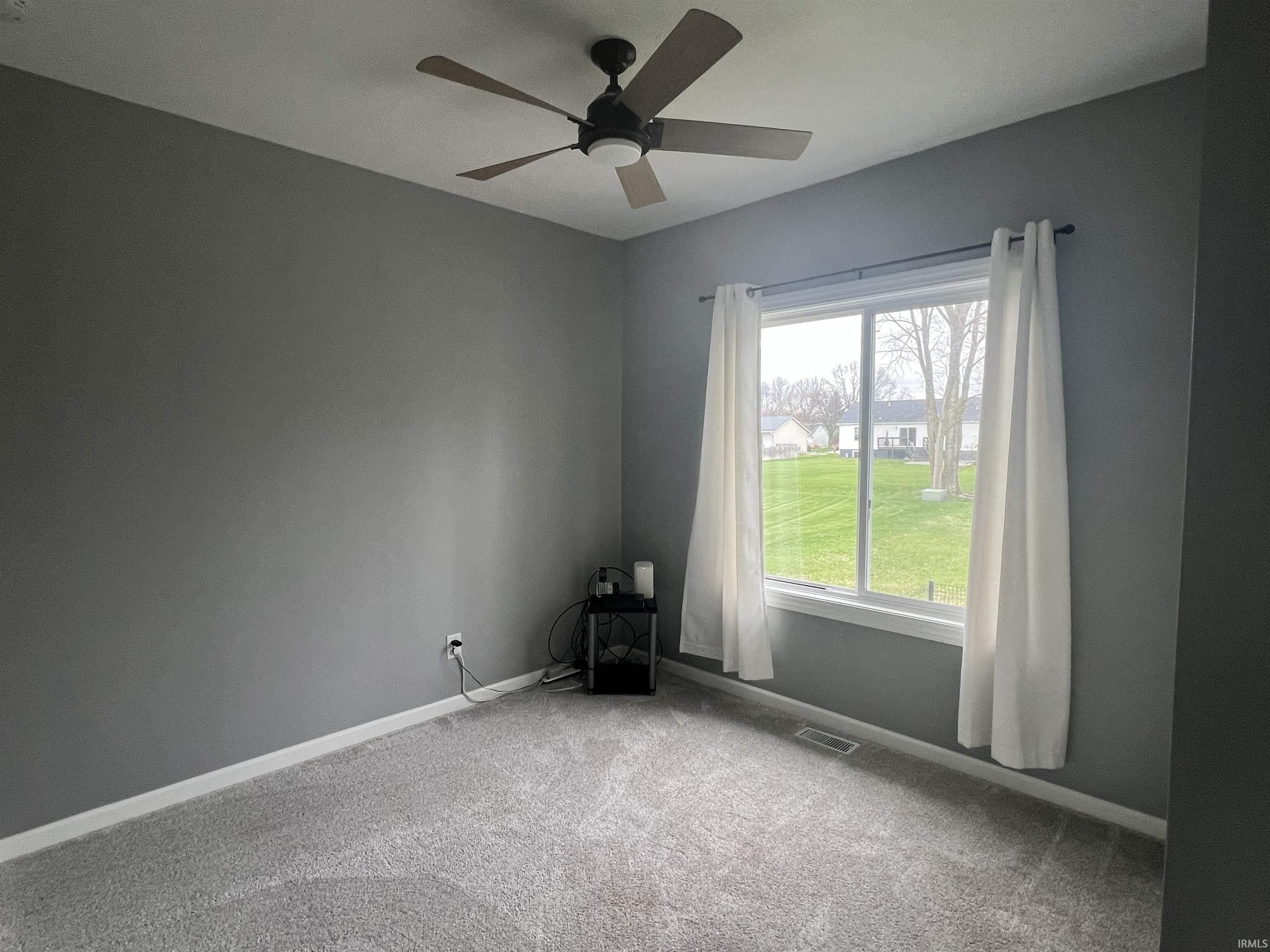 Unfurnished room with light colored carpet and a ceiling fan