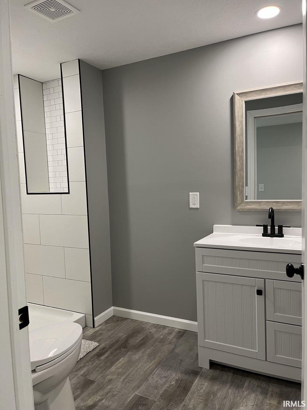 Full bathroom featuring vanity, dark wood-style flooring, and a textured ceiling