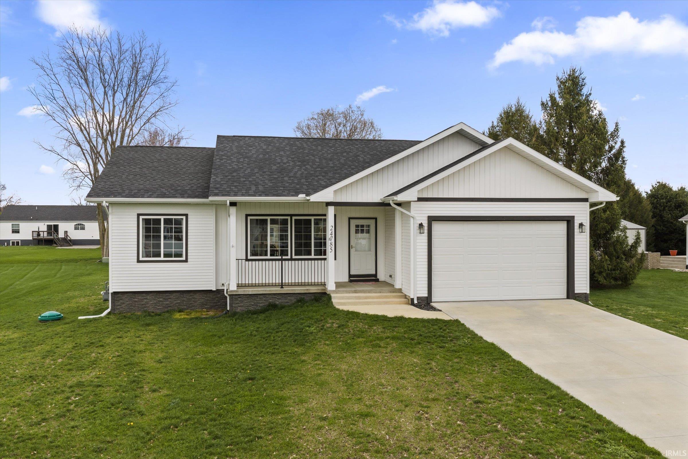 Ranch-style home with a front lawn, an attached garage, roof with shingles, and concrete driveway