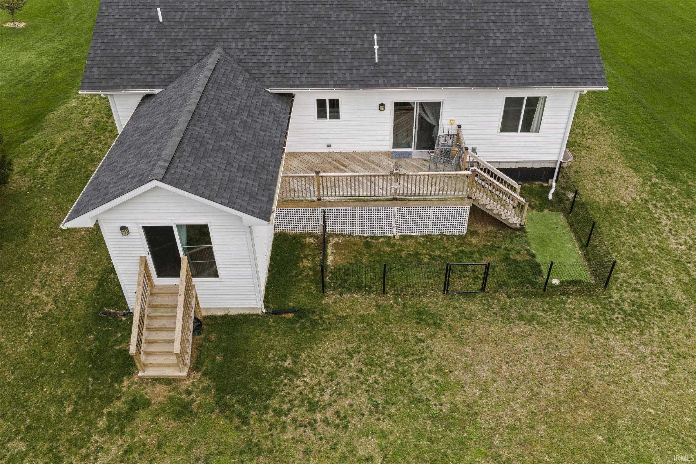 Rear view of property featuring roof with shingles, a yard, and a deck