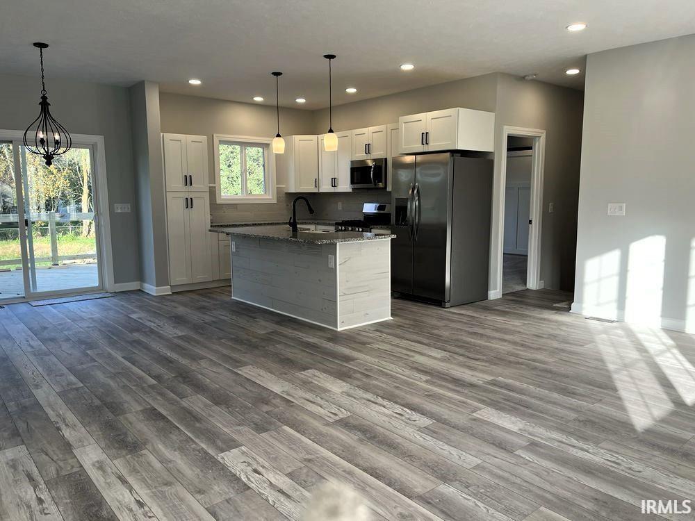 Kitchen featuring white cabinets, stainless steel appliances, dark wood-style floors, and dark stone countertops