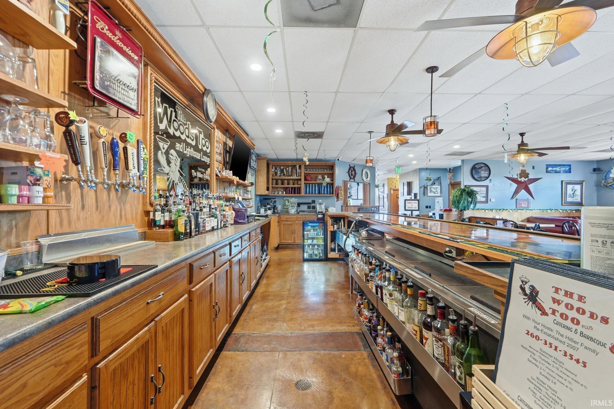Miscellaneous room with recessed lighting, a paneled ceiling, a community bar, and wine cooler