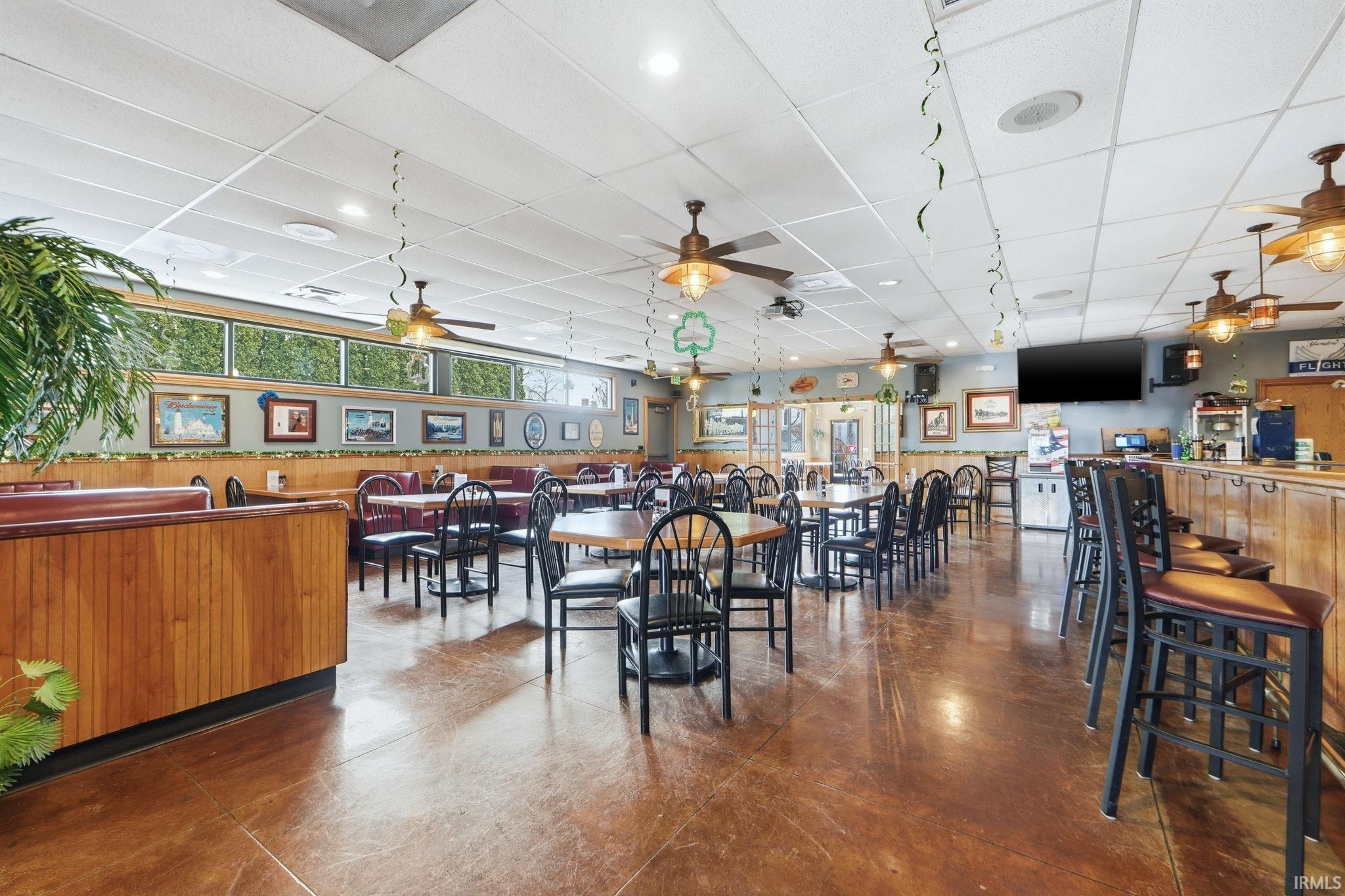 Dining space featuring wainscoting, a drop ceiling, and wooden walls