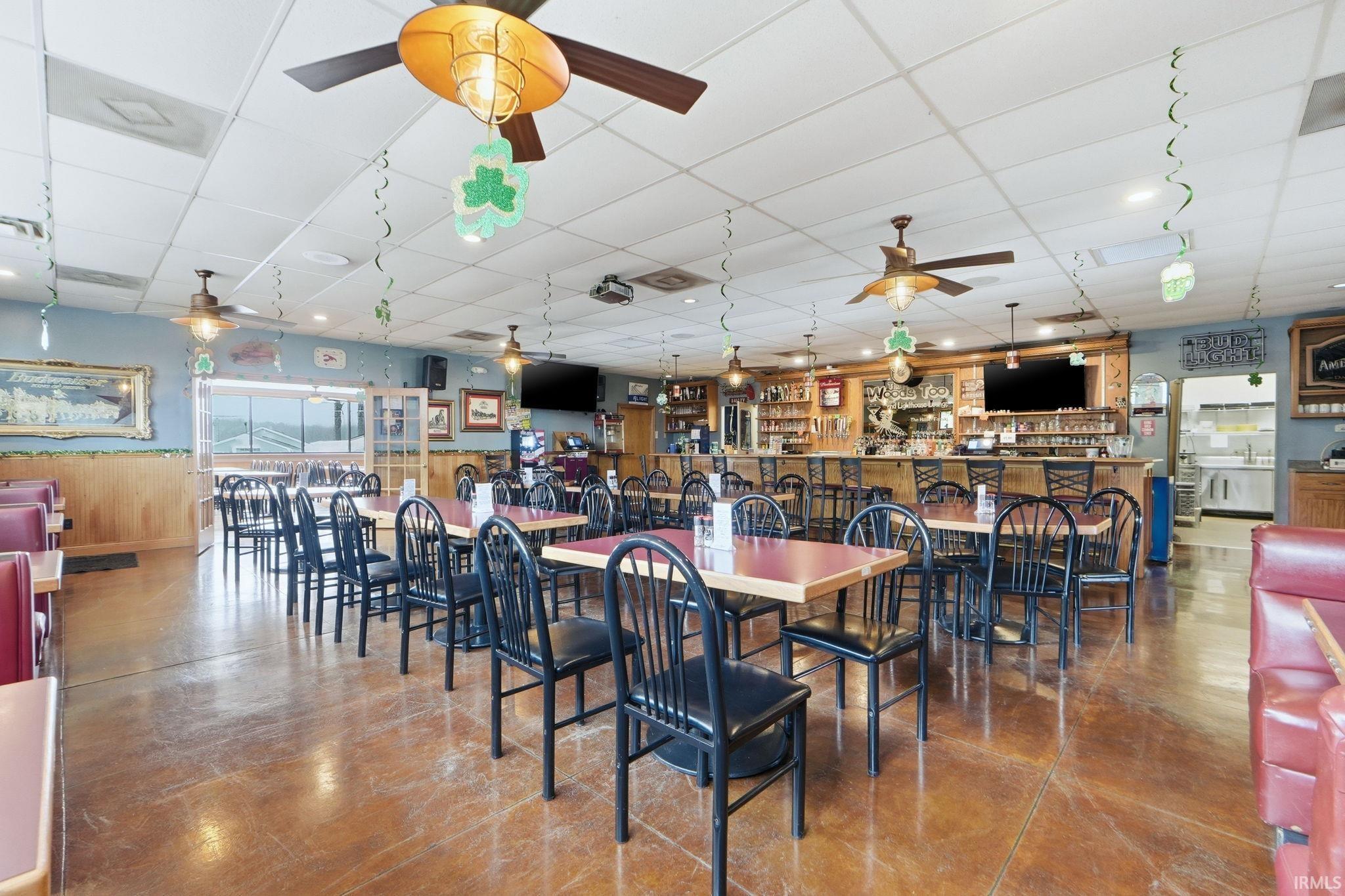 Dining room with a paneled ceiling, finished concrete floors, and wainscoting