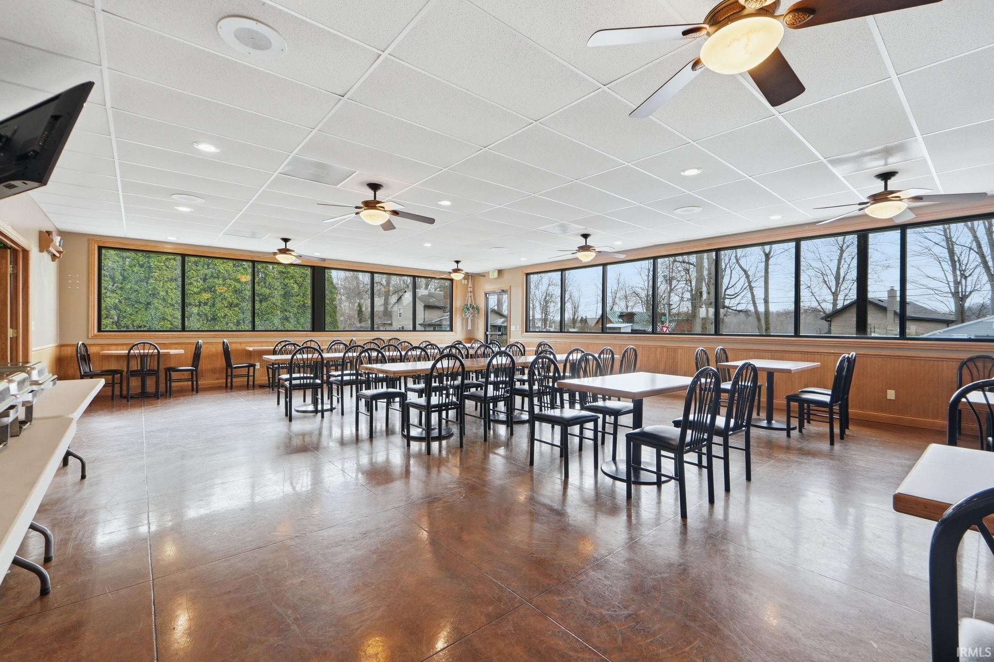 Dining room with a paneled ceiling, wood walls, and recessed lighting