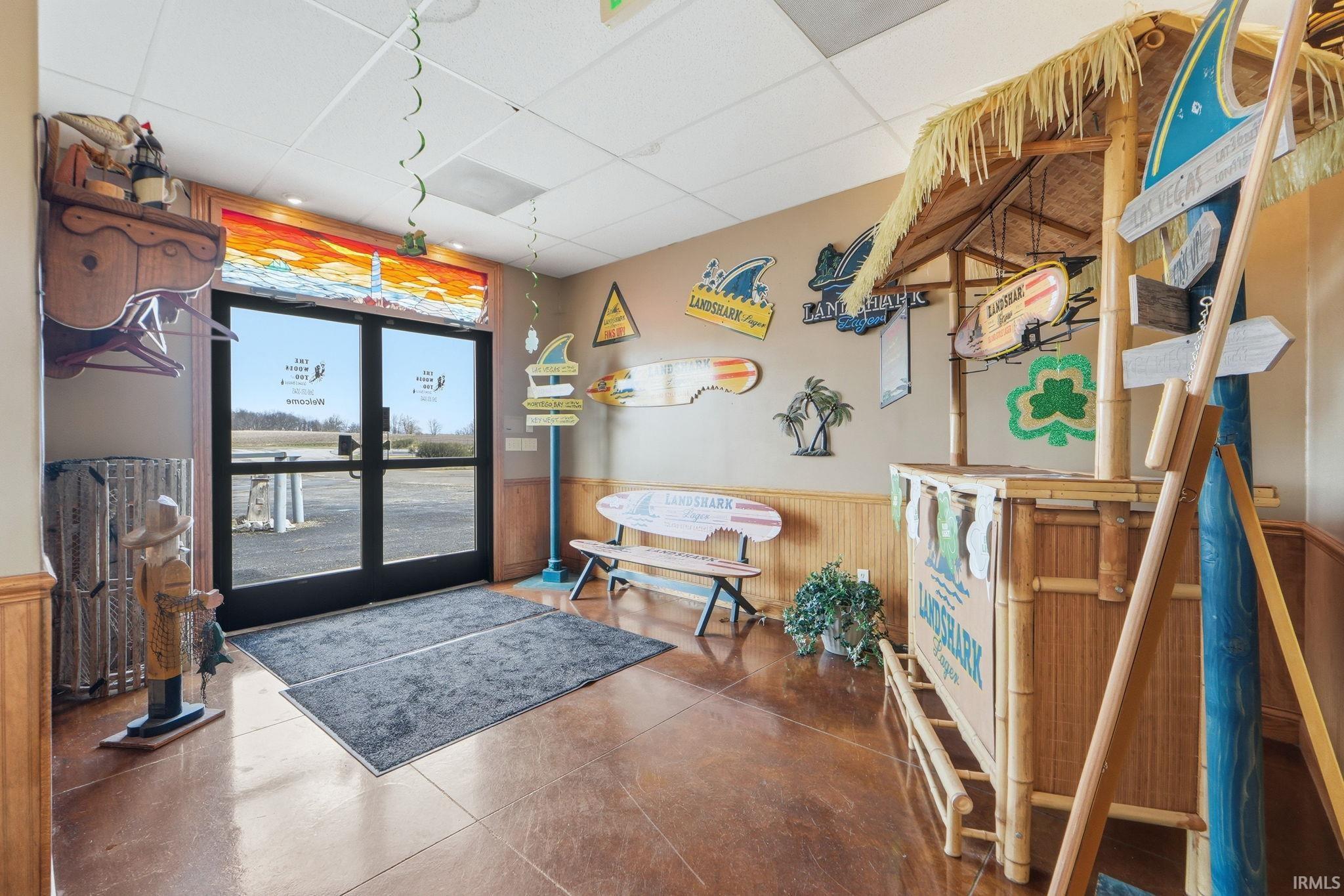 Common area featuring a wainscoted wall, a paneled ceiling, and wood walls