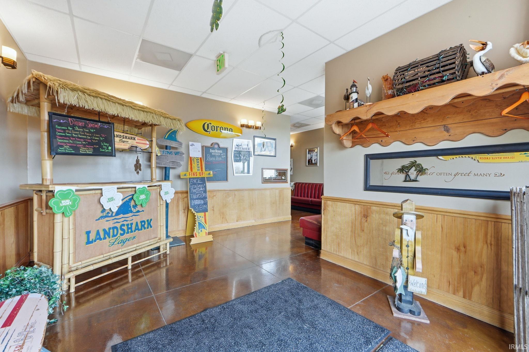 Welcome area with a wainscoted wall, a paneled ceiling, and wood walls