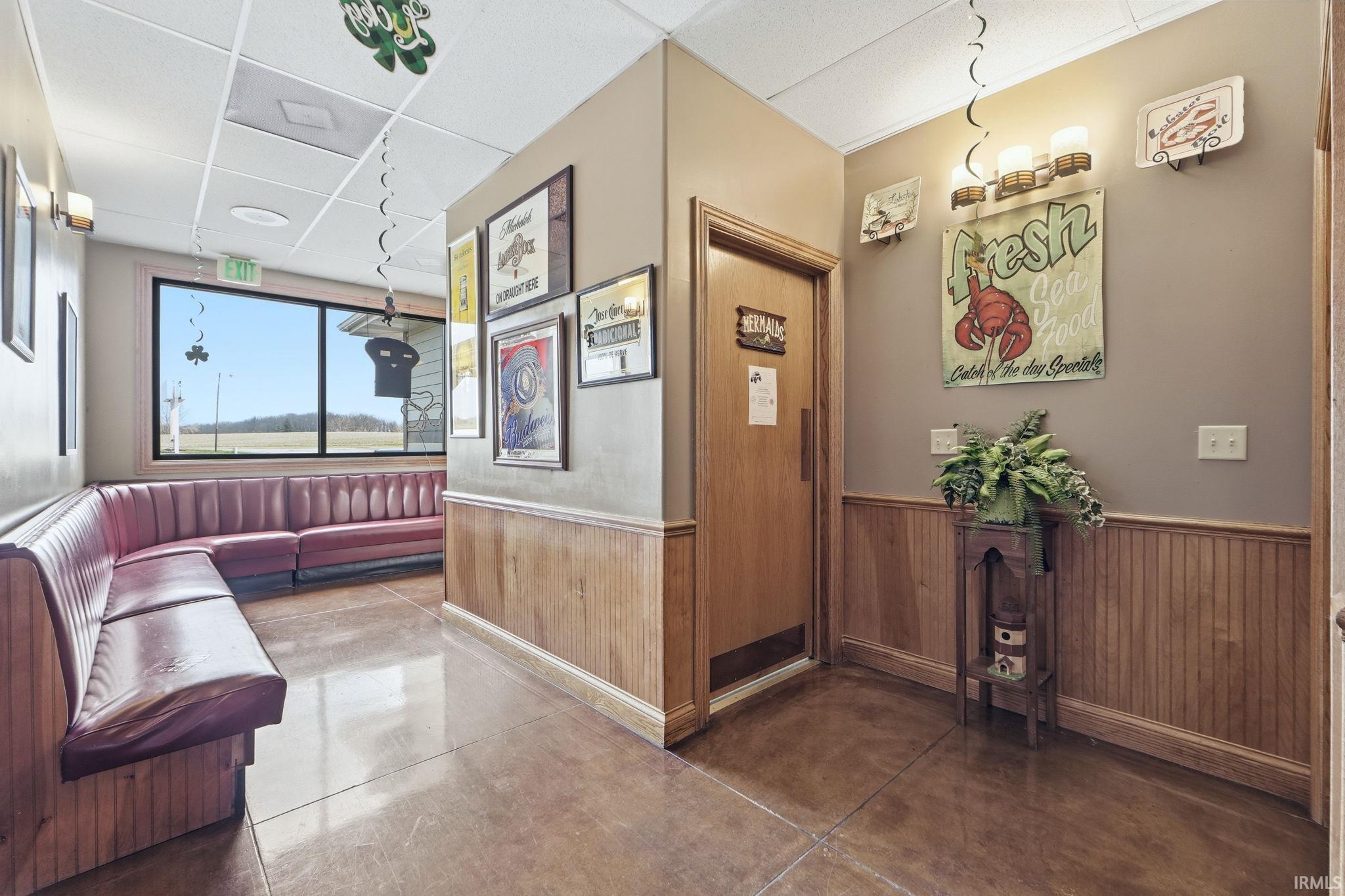 Community lobby featuring a paneled ceiling, a wainscoted wall, and wood walls